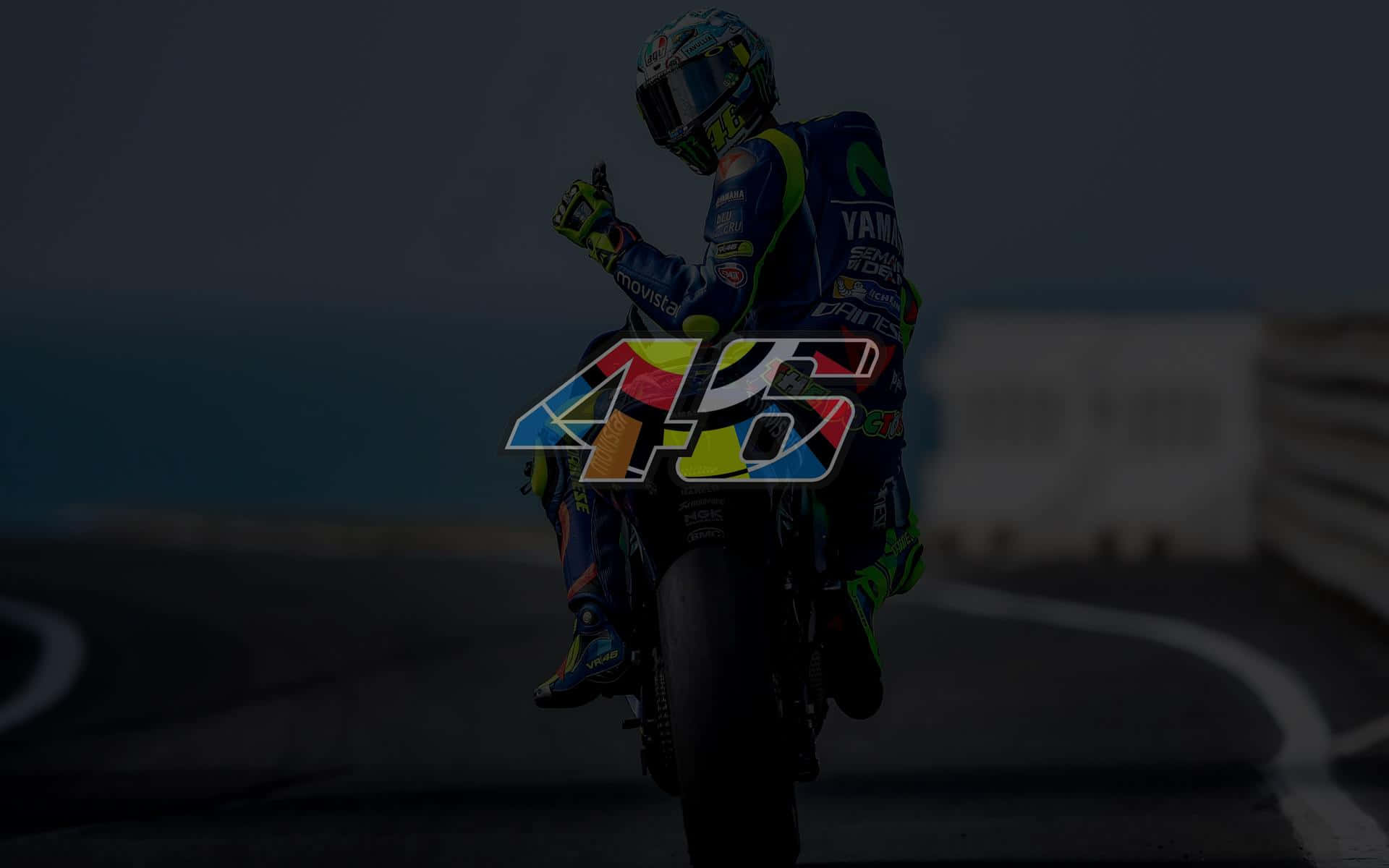Racing 桌布 壁紙 — 一位身穿藍色裝備的摩托車賽車手在賽道上慶祝，並帶有大型彩色46標誌覆蓋層。
