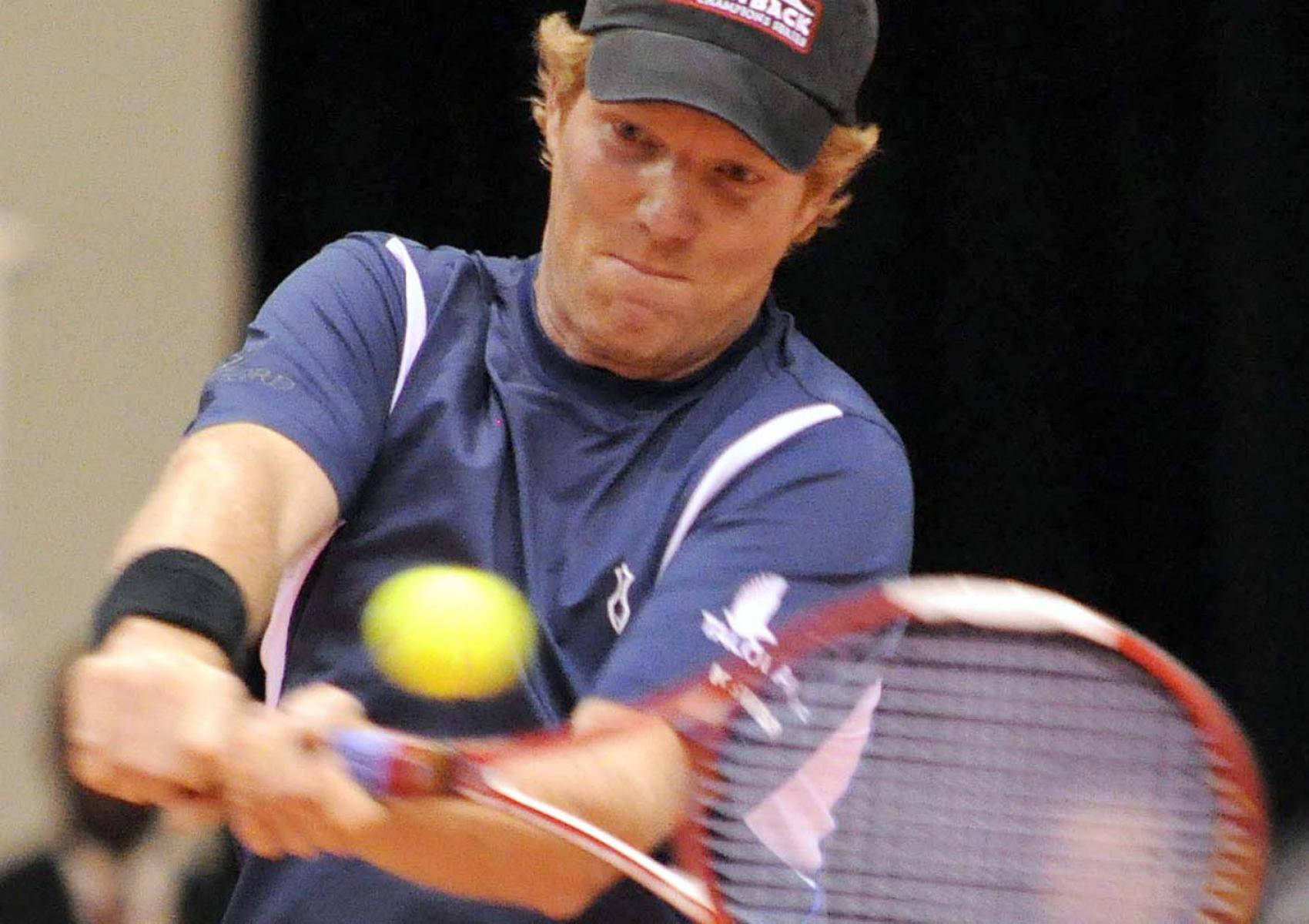 Tennis 桌布 壁紙 — 一位身穿藍色襯衫的男性網球選手在室內用力揮拍擊向黃色網球。