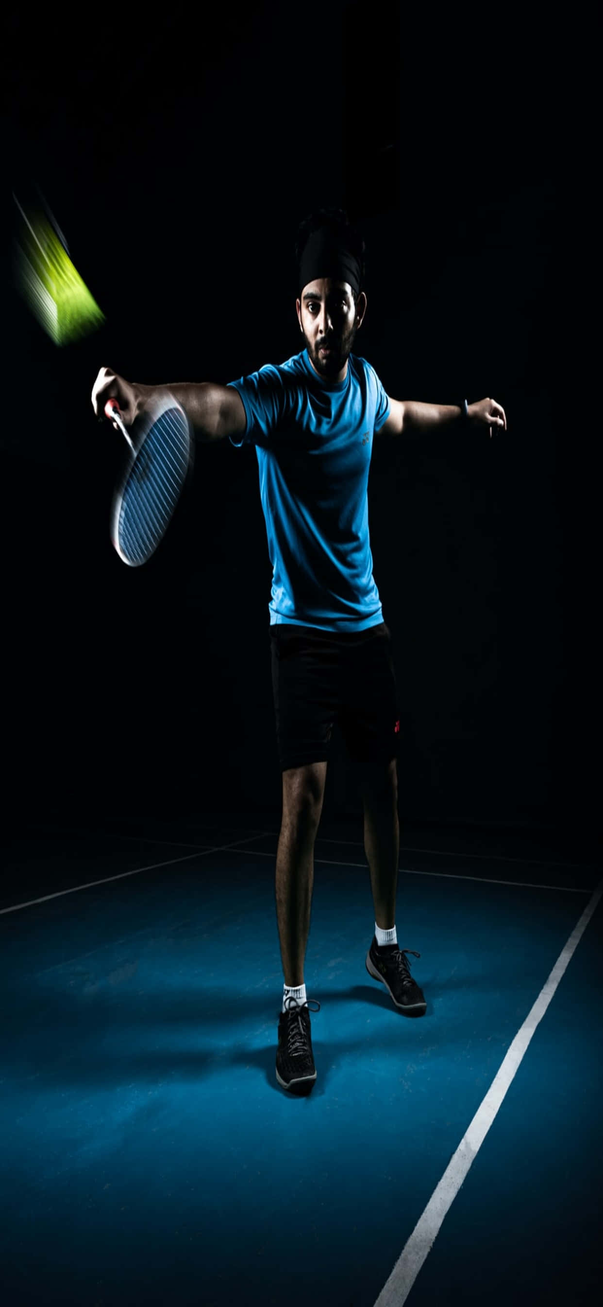 iPhone Xs Max Badminton 桌布 壁紙 — 一位身穿藍色襯衫的網球選手在藍色球場上，在深色背景下揮動球拍，帶有動態模糊效果。