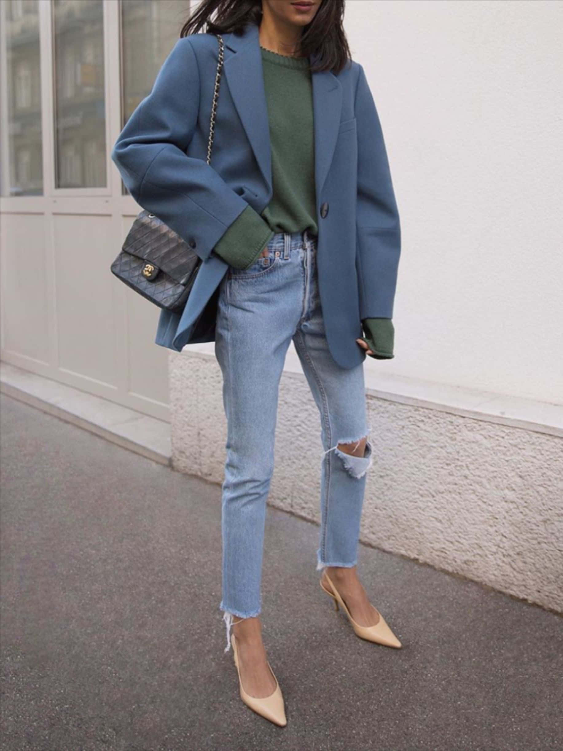 Winter Fashion 桌布 壁紙 — 一位身穿藍色西裝外套、綠色毛衣、破洞牛仔褲和米色高跟鞋的女性自信地走在城市人行道上。