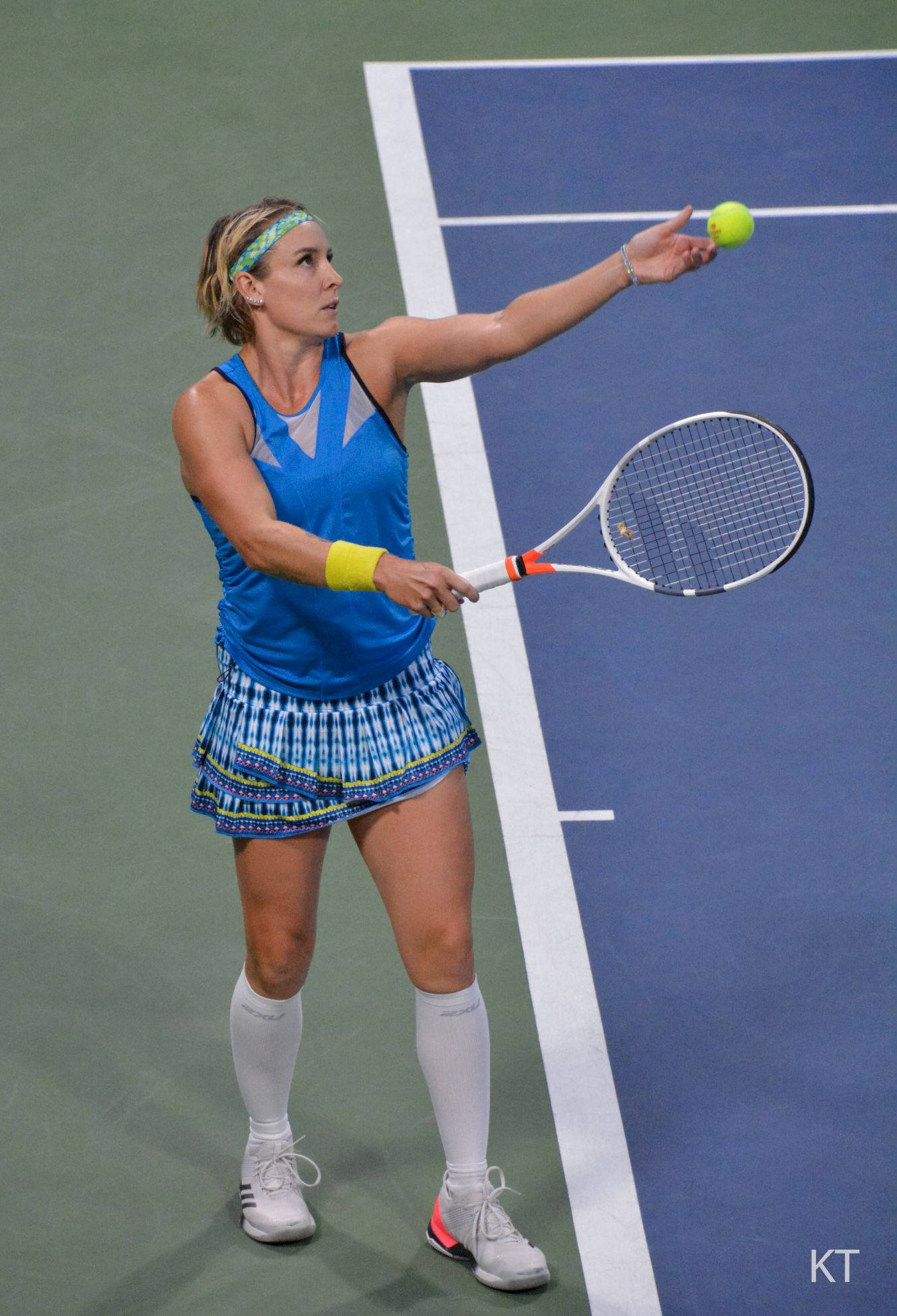 Tennis 桌布 壁紙 — 一位身穿藍色運動裝備的女網球運動員在明亮燈光下的硬地球場準備發球。