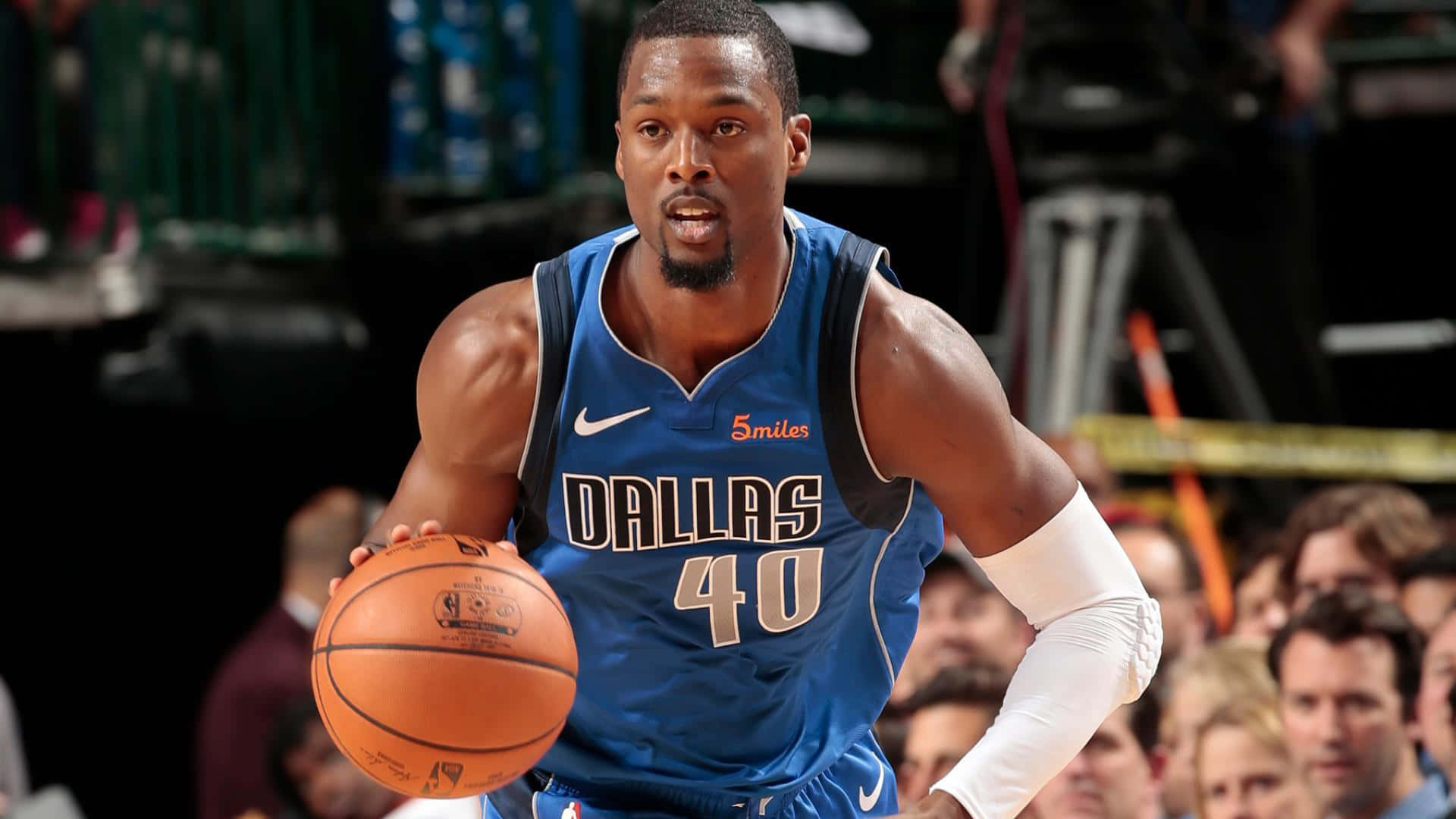 NBA 桌布 壁紙 — 一位身穿藍色達拉斯球衣的專注籃球運動員，在明亮的場館燈光下於激烈比賽中運球。