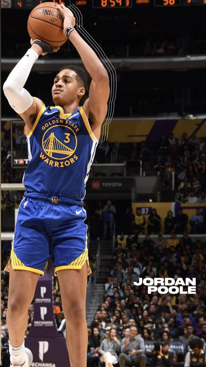 NBA 桌布 壁紙 — 一位身穿藍色金州勇士隊球衣的籃球運動員在明亮的場館燈光下，身後擠滿了觀眾，跳投出手。