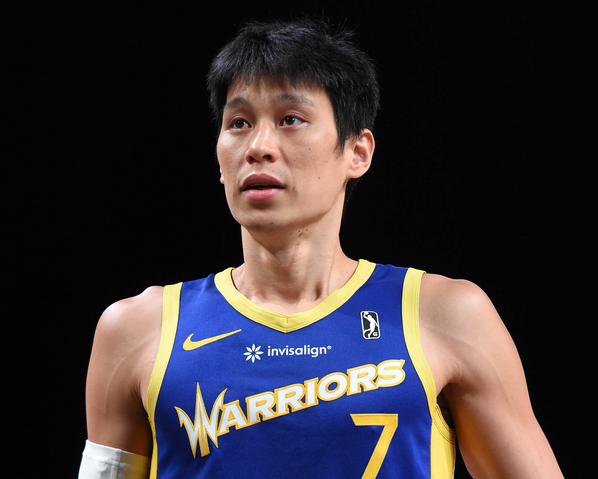 Lin 桌布 壁紙 — 一位身穿藍黃勇士隊7號球衣、神情專注的籃球運動員站在黑色背景前。