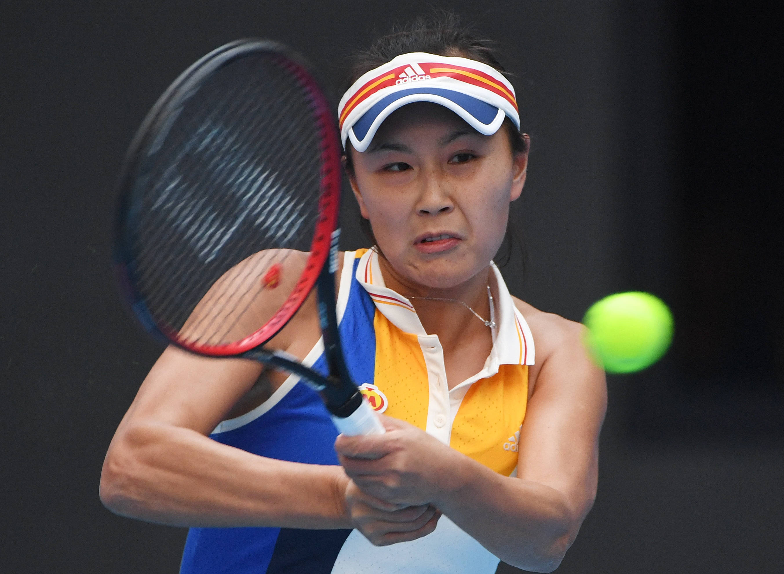 運動 桌布 壁紙 — 一位身穿藍黃色球衣的女網球運動員，全神貫注地揮拍擊打一顆亮綠色的球。