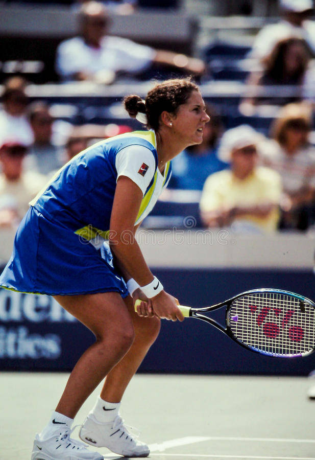 Monica Seles 桌布 壁紙 — 一位身穿藍黃色裝備的女網球選手在陽光明媚的球場上向前衝刺，手持球拍。