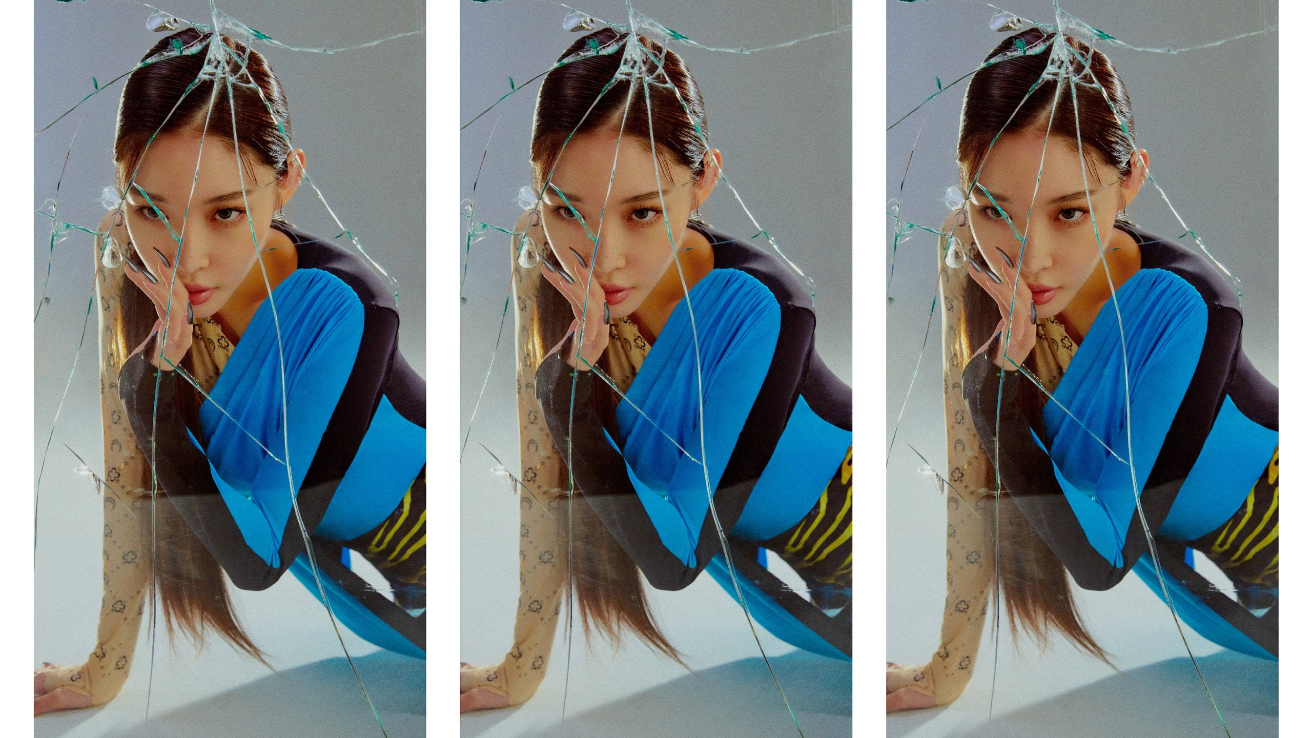 Chungha 桌布 壁紙 — 一位身穿藍黑服裝的女性在破碎的玻璃後面擺姿勢，表情嚴肅。