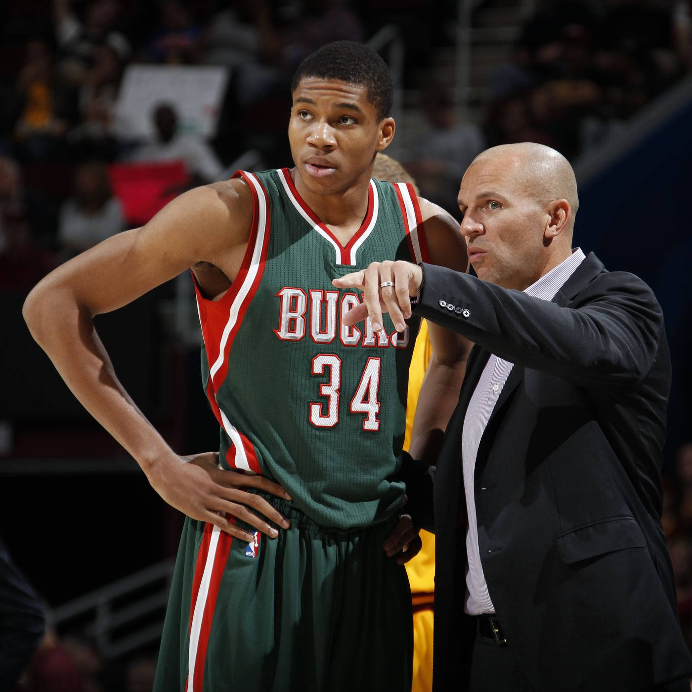 NBA 桌布 壁紙 — 一位身穿西裝的籃球教練在比賽中專注地指向一位身穿34號球衣的密爾瓦基公鹿隊球員。