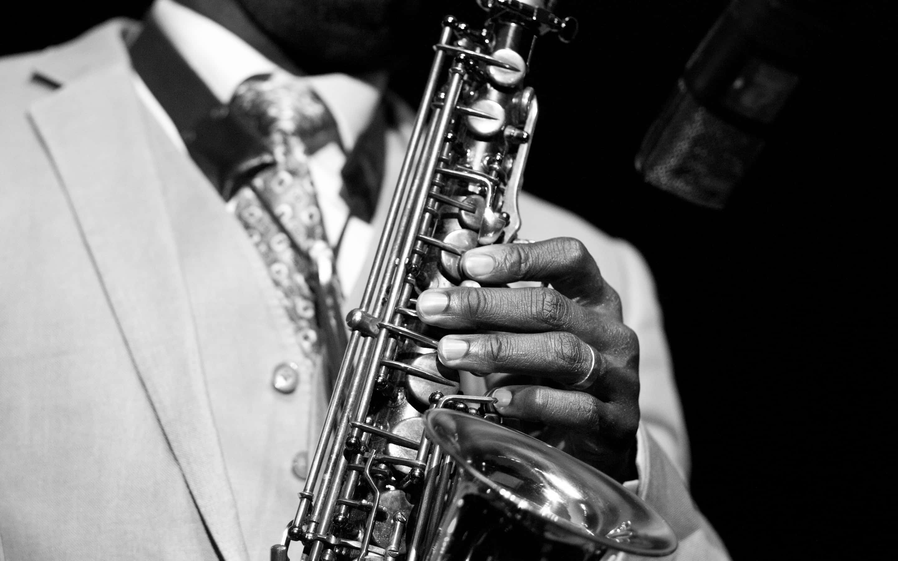 Jazz 桌布 壁紙 — 一位身穿西裝的音樂家在戲劇性的黑白燈光下吹奏薩克斯風，附近有一個麥克風。