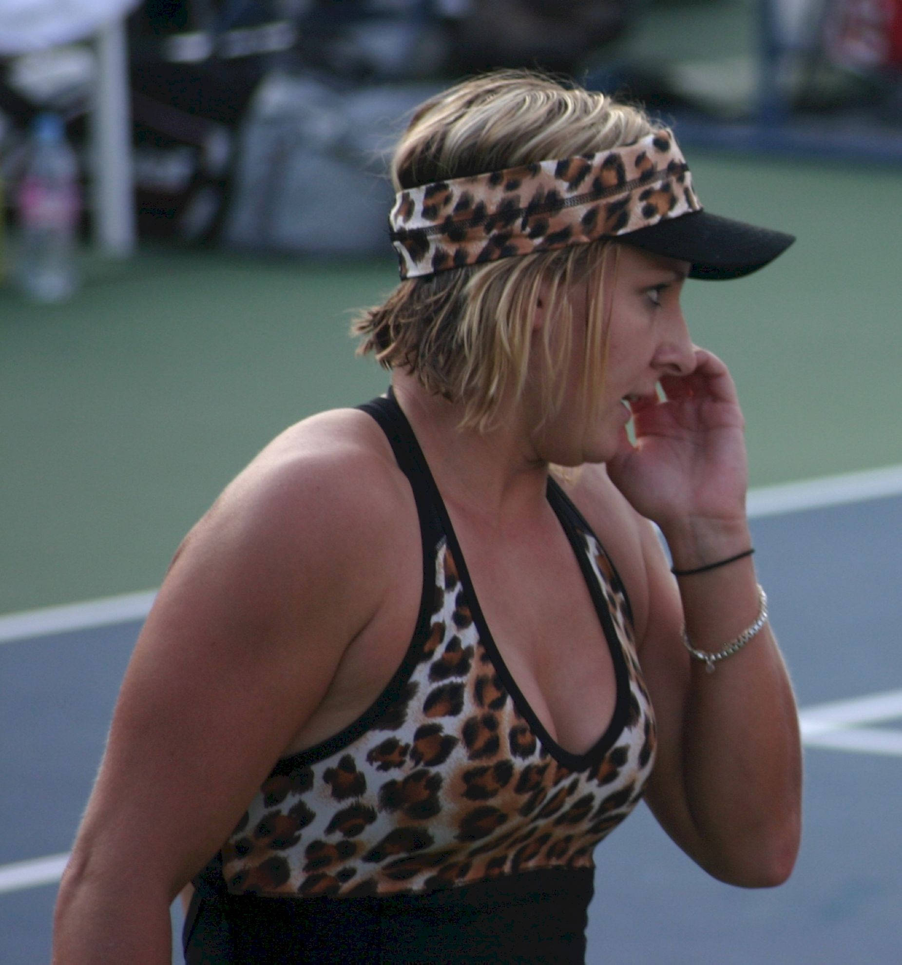 Tennis 桌布 壁紙 — 一位身穿豹紋服裝和遮陽帽的女網球運動員在綠色球場上停下來，手靠近嘴巴。