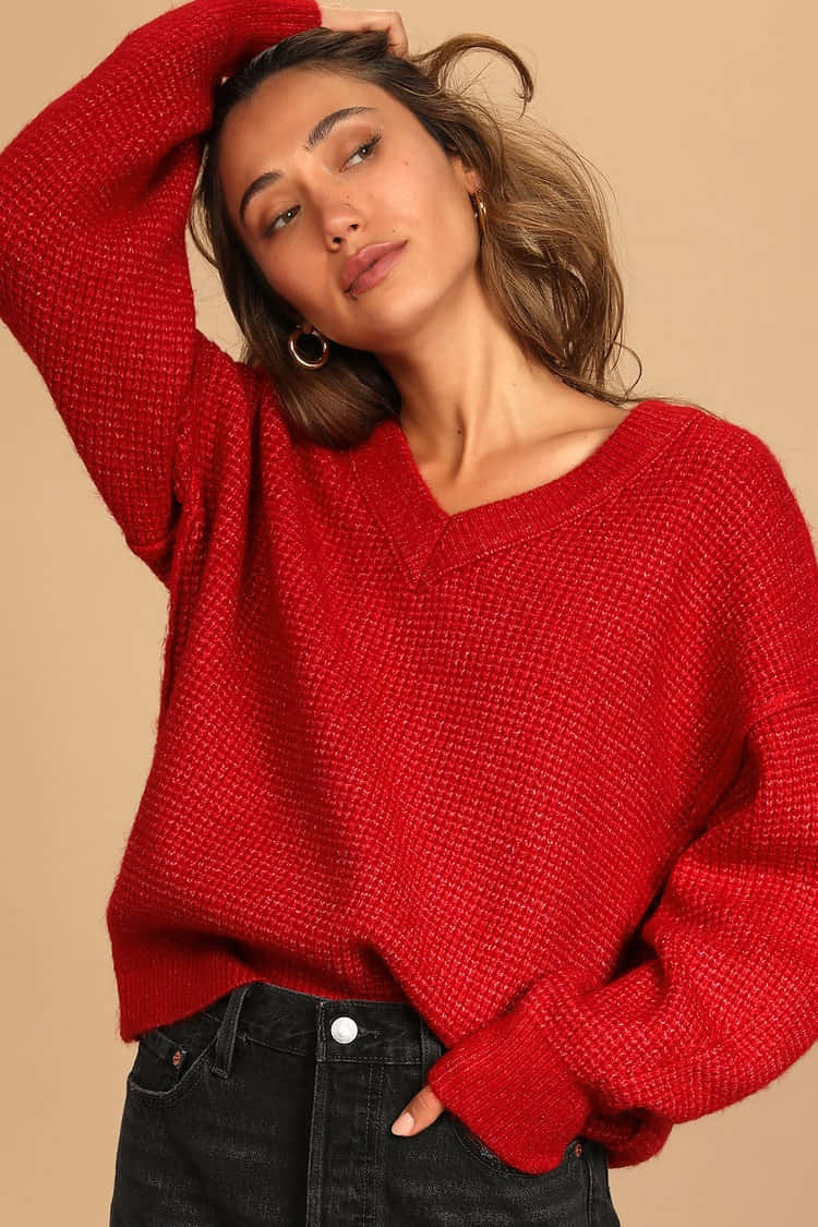 Red Sweater 桌布 壁紙 — 一位身穿質感紅色毛衣的女性，在米色背景前將一隻手放在頭髮上擺姿勢。