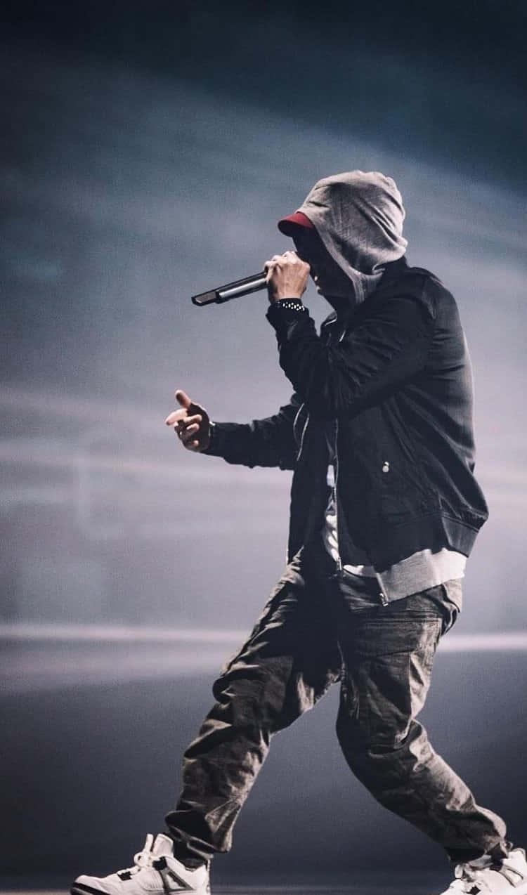 Drake 桌布 壁紙 — 一位身穿連帽衫和帽子的饒舌歌手在煙霧彌漫的舞台上，在戲劇性的燈光下激情表演。