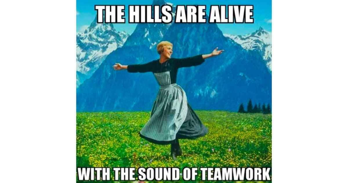 Teamwork Memes 桌布 壁紙 — 一位身穿連衣裙的女子在陽光明媚、開滿黃花的草地上快樂地旋轉，身後是白雪覆蓋的山峰。