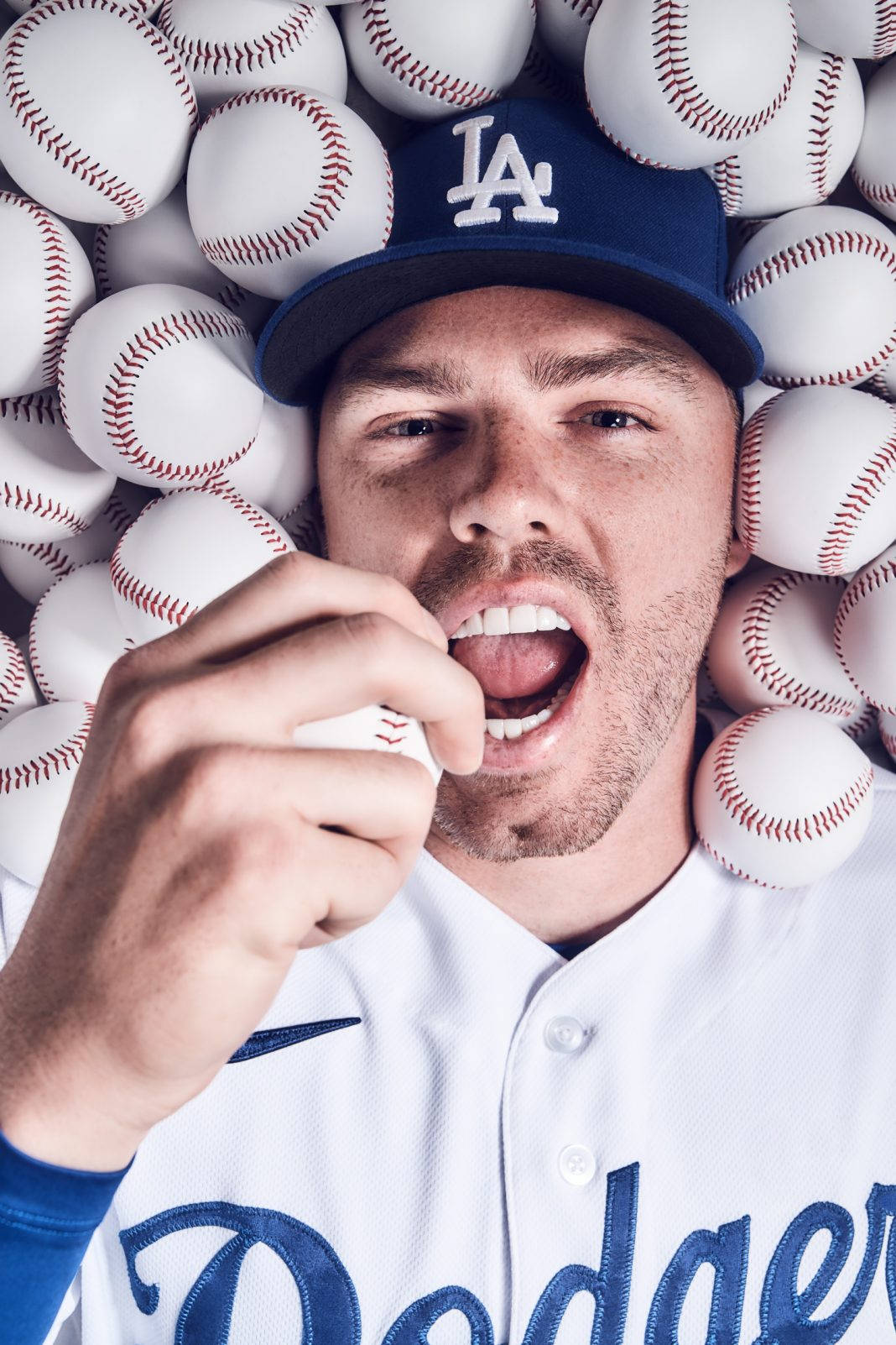 Freddie Freeman 桌布 壁紙 — 一位身穿道奇隊制服的棒球運動員在攝影棚拍攝中，被棒球包圍著微笑。