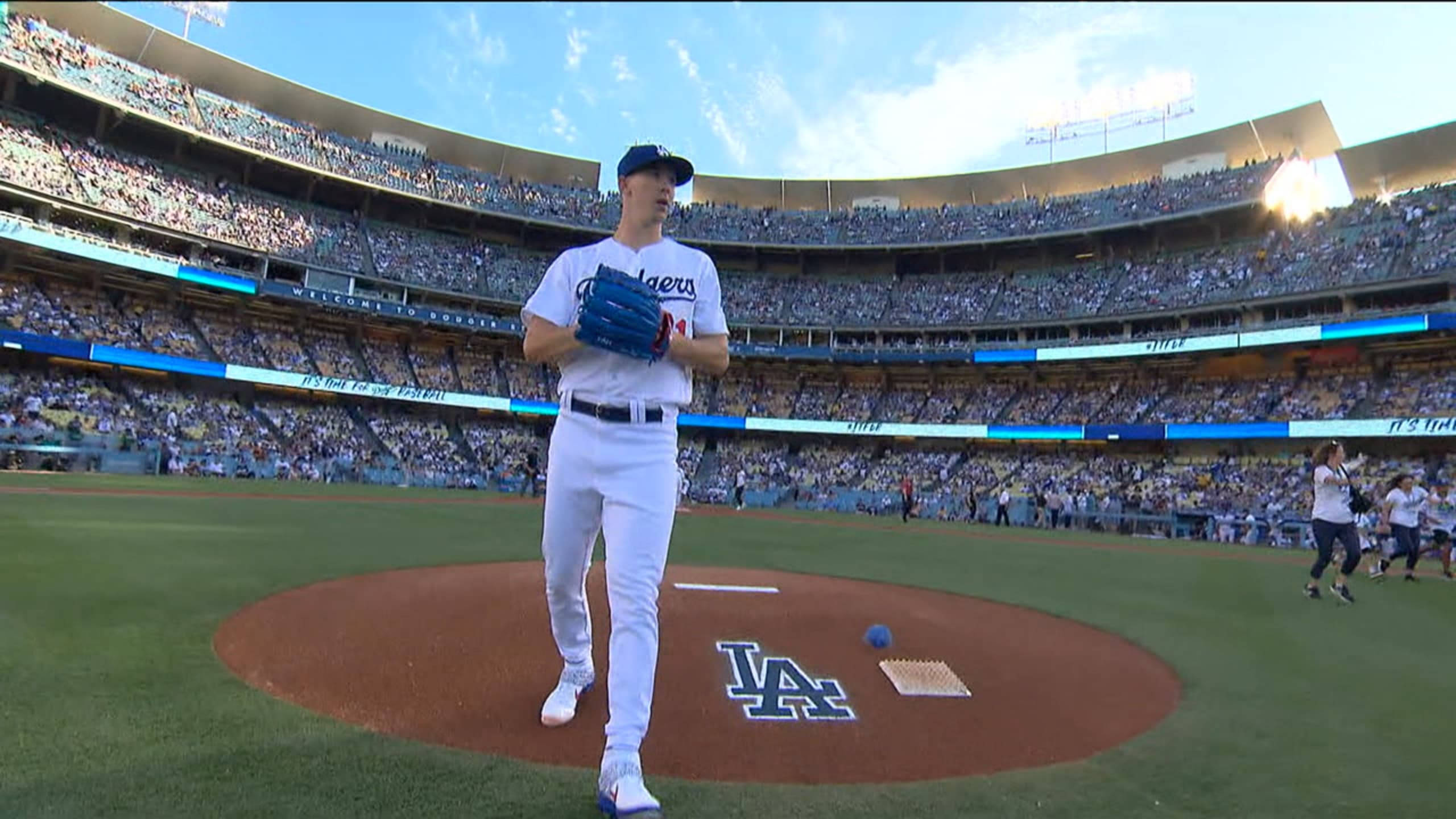 walker buehler 桌布 壁紙 — 一位身穿道奇隊球衣的棒球投手站在投手丘上，背後是晴朗的天空和座無虛席的球場。