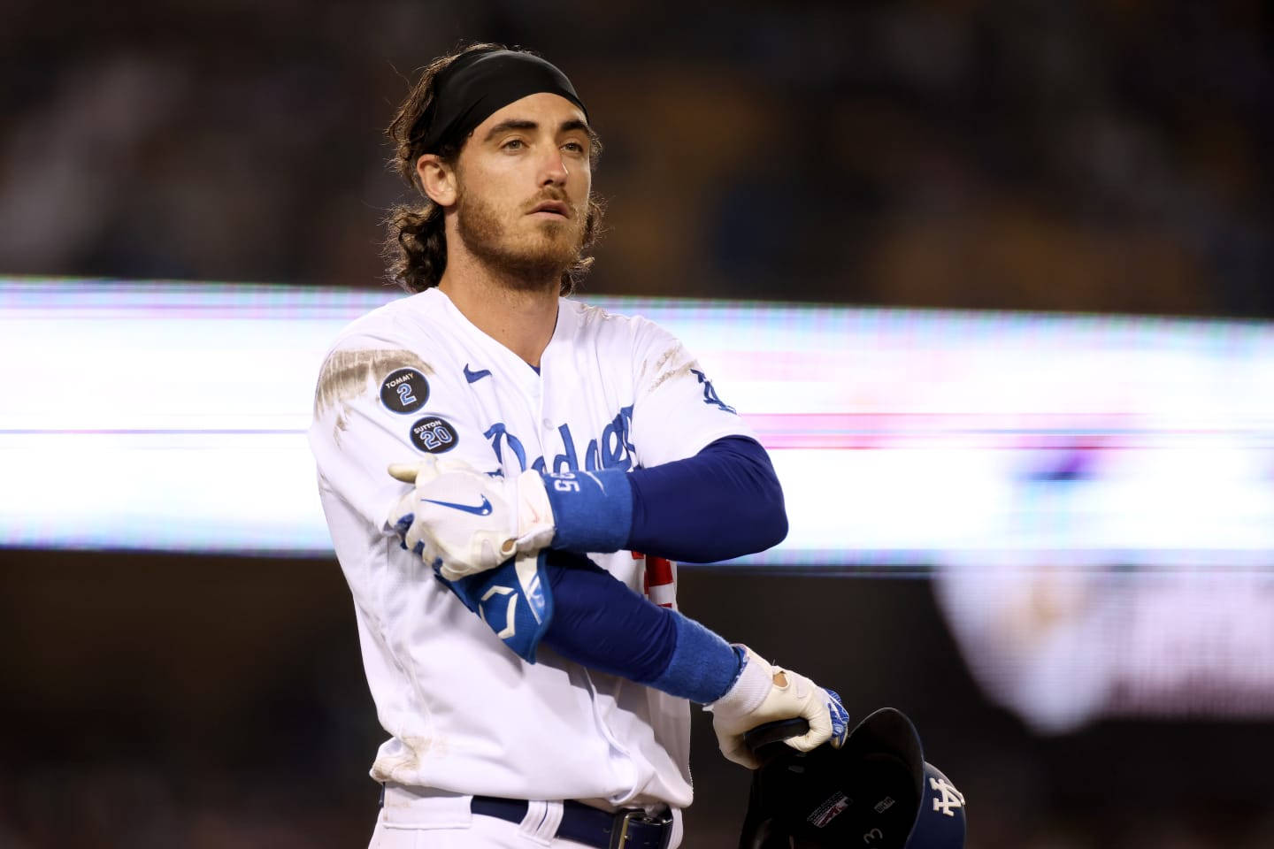 Cody 桌布 壁紙 — 一位身穿道奇隊球衣的棒球選手在球場燈光下交叉雙臂，手持頭盔站立。