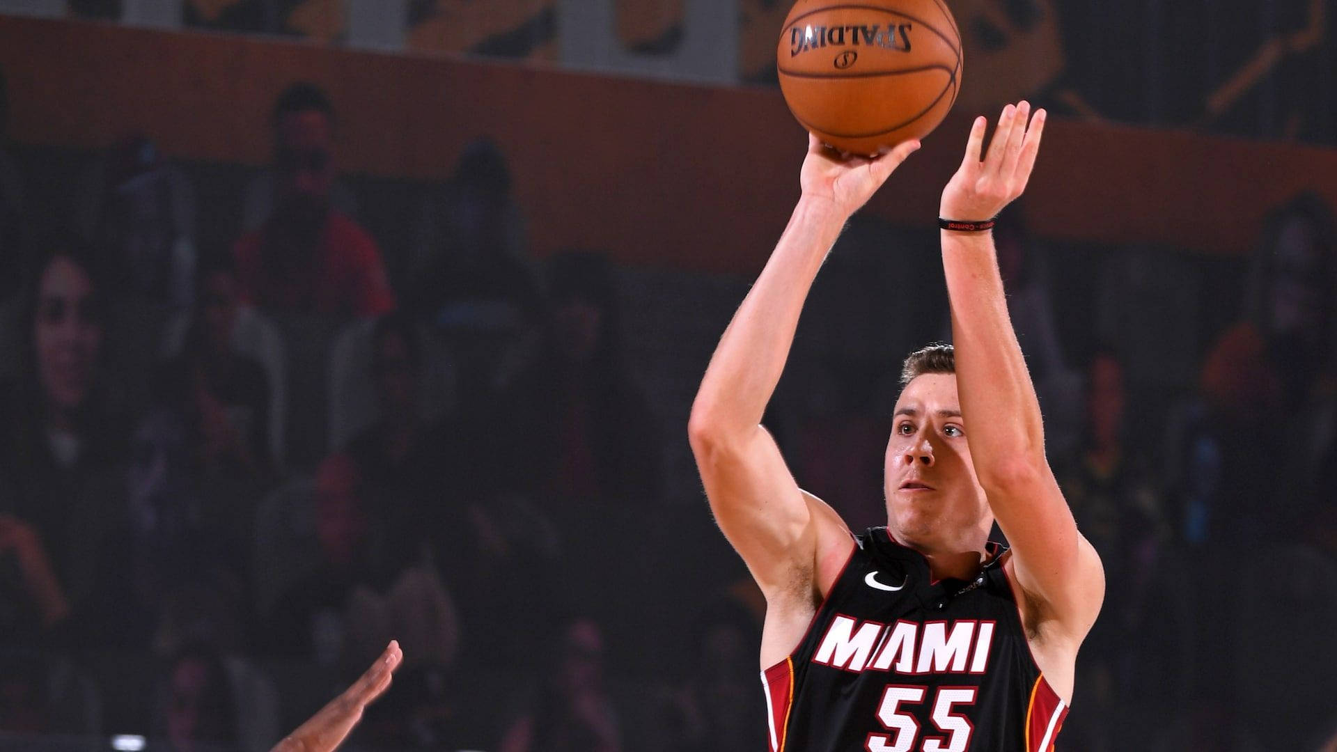 duncan robinson 桌布 壁紙 — 一位身穿邁阿密熱火球衣的籃球運動員，在場館燈光下專注地投出Spalding籃球。