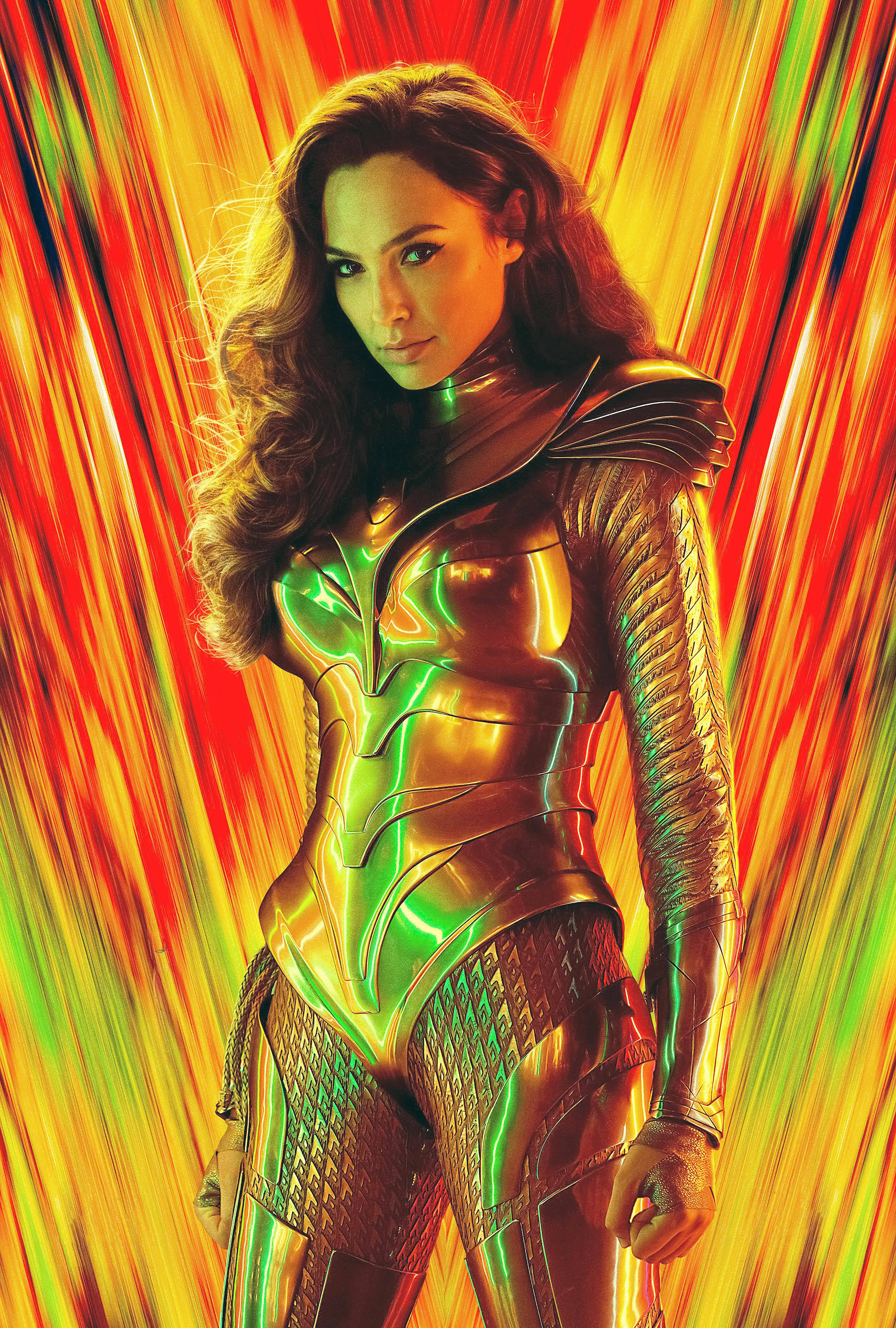 Wonder Woman 1984 桌布 壁紙 — 一位身穿金屬金色和綠色套裝的女超級英雄自信地站在由紅、橙、黃色組成的鮮豔條紋背景前。
