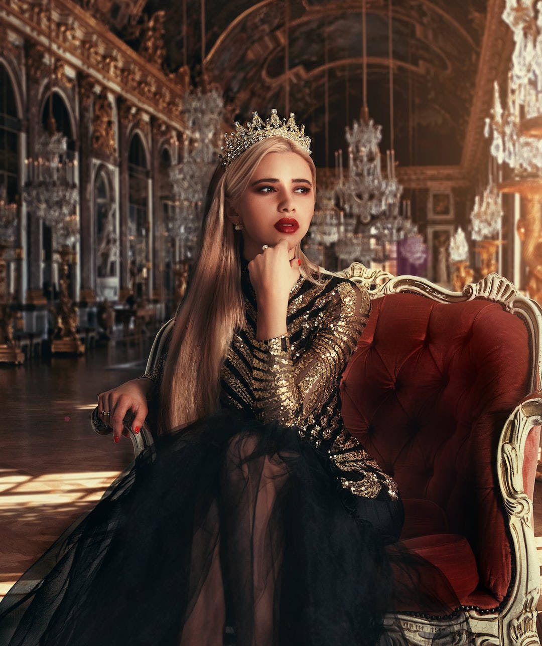 Princess 桌布 壁紙 — 一位身穿金色亮片長袍、頭戴王冠的尊貴女性，端坐在陽光普照的華麗宮殿大廳中的紅色天鵝絨寶座上。