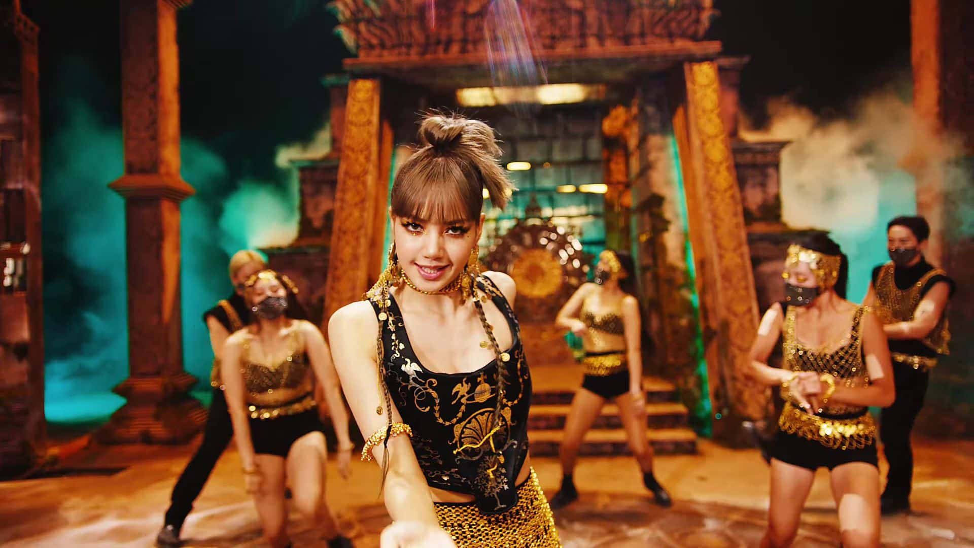 Lalisa 桌布 壁紙 — 一位身穿金色和黑色舞蹈服裝的女性在一個類似寺廟的舞台上帶領一場編排好的表演，舞台上有發光的綠色煙霧和戲劇性的燈光。