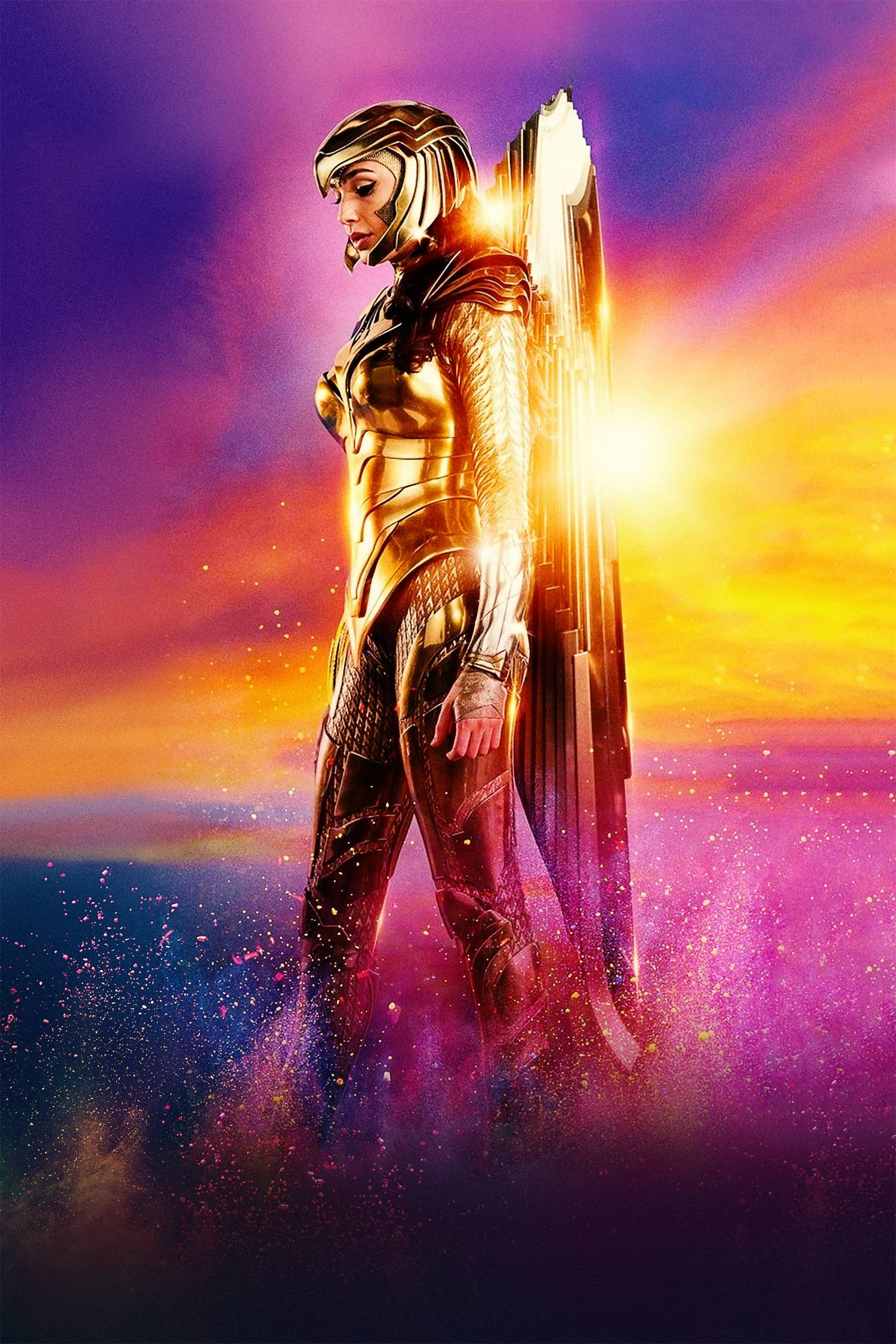Wonder Woman 1984 桌布 壁紙 — 一位身穿金色盔甲的女戰士，在充滿活力的日落天空下，閃爍的粒子在她周圍旋轉，英勇地站立著。