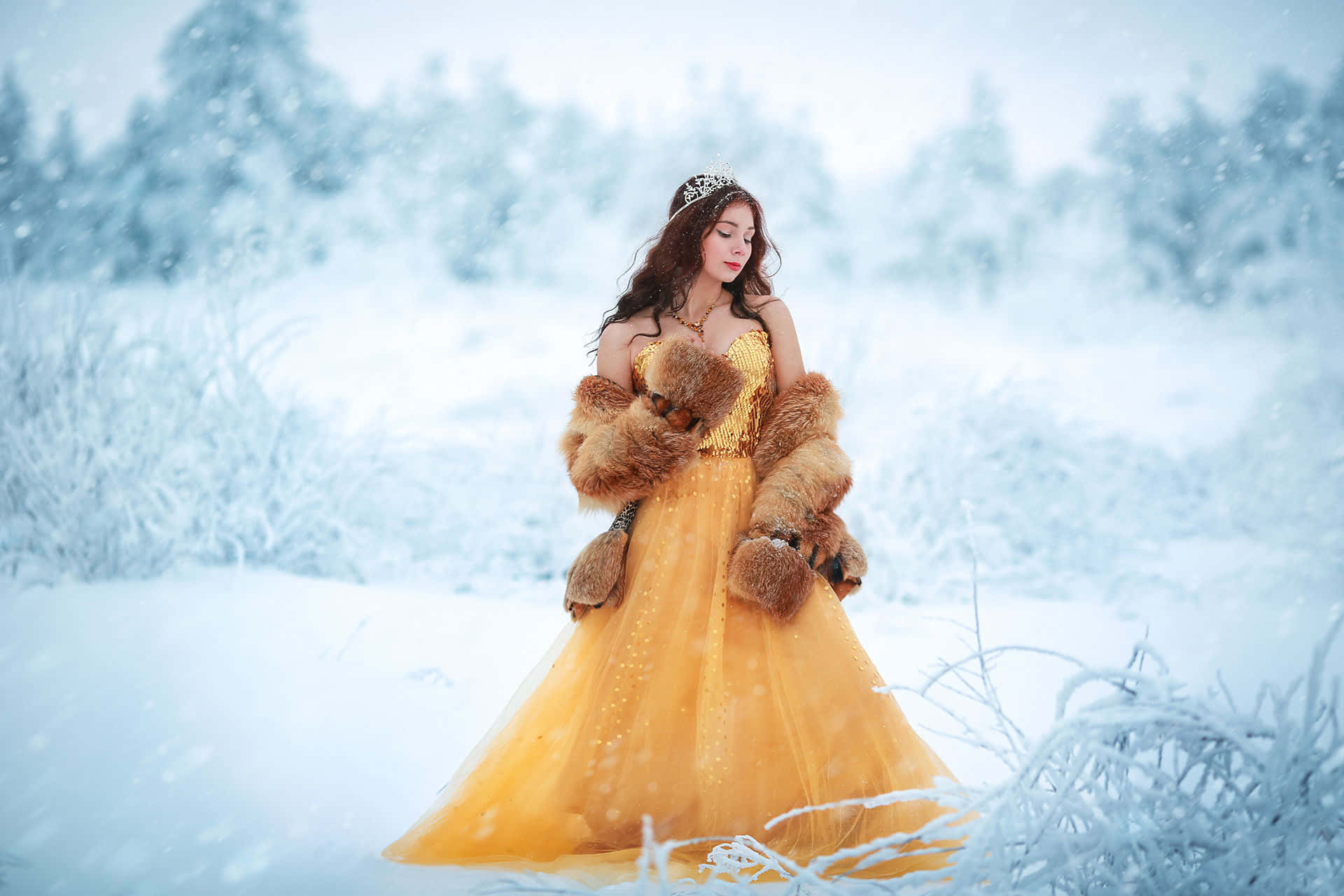 Yellow Dress 桌布 壁紙 — 一位身穿金色長袍和毛皮披肩的女性優雅地站在白雪皚皚的冬季森林中，雪花飄落在她周圍。