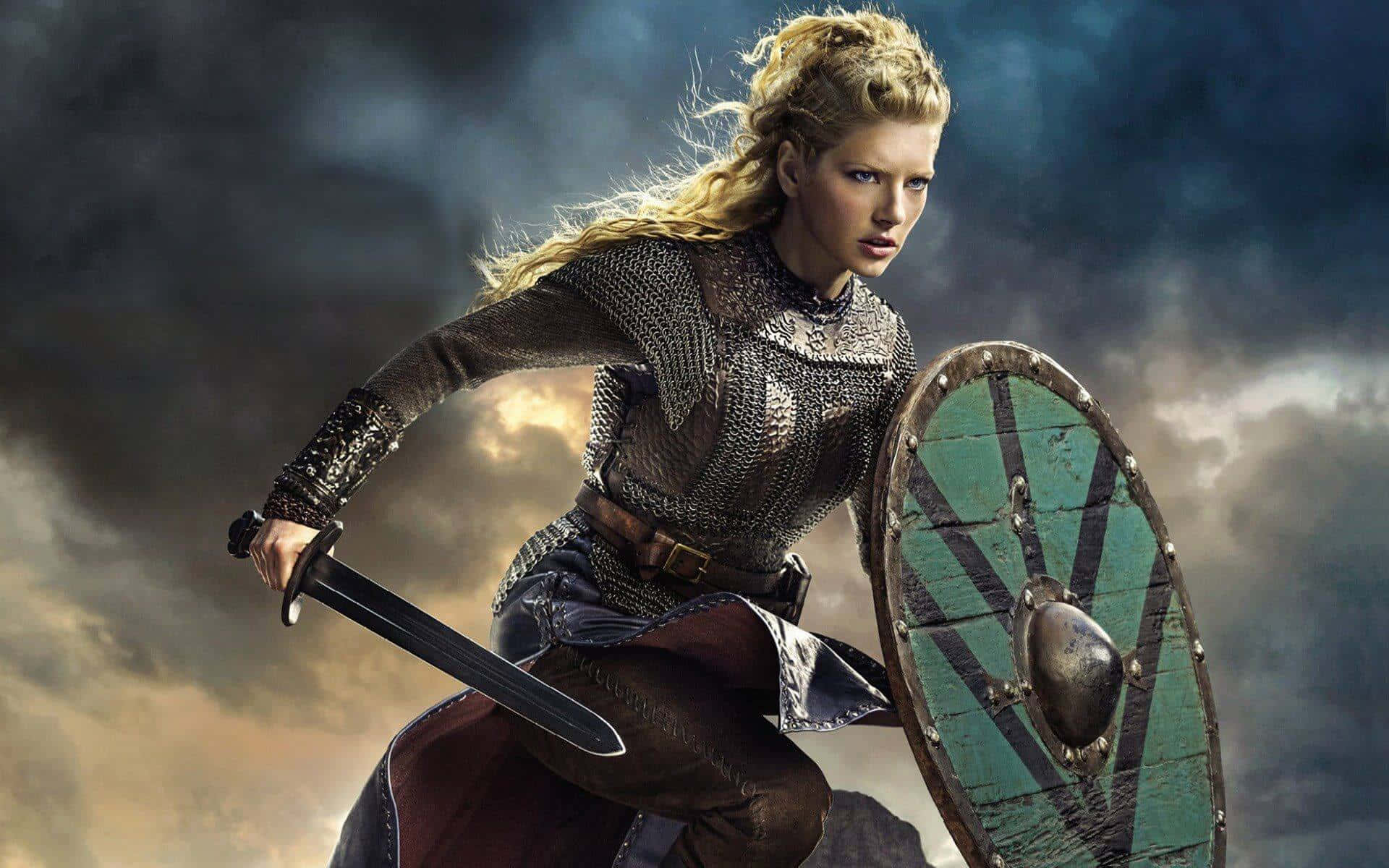 Female Viking Warriors 桌布 壁紙 — 一位身穿鎖子甲和皮革的兇猛金髮戰士，在暴風雨的天空下揮舞劍與盾向前衝鋒。