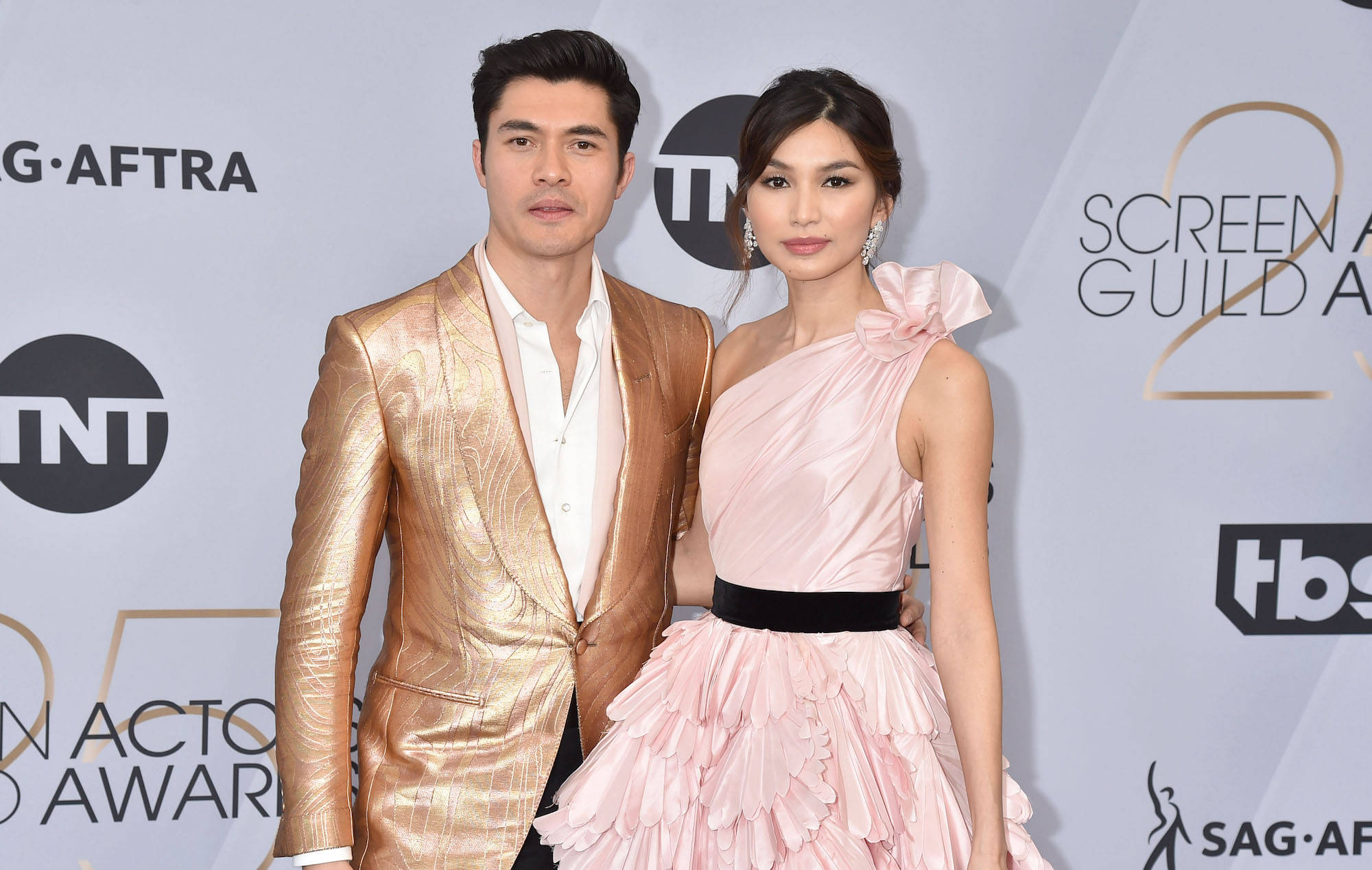 Gemma Chan 桌布 壁紙 — 一位身穿閃亮金色西裝的男士和一位身穿粉紅色荷葉邊禮服的女士在美國演員工會獎紅地毯上一起擺姿勢。