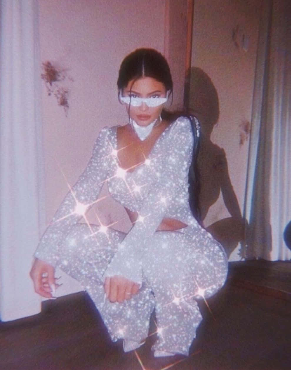 Boujee Aesthetic 桌布 壁紙 — 一位身穿閃亮銀色連身衣的女性，戴著白色太陽眼鏡，自信地蹲在室內。