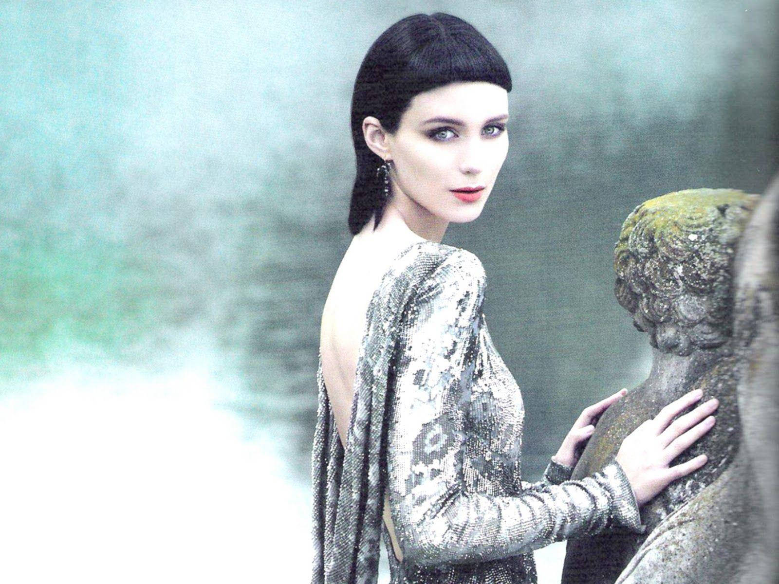 風景 桌布 壁紙 — 一位身穿閃亮銀色長裙的女性，在迷霧般的綠色背景下，輕輕觸摸長滿青苔的石像。