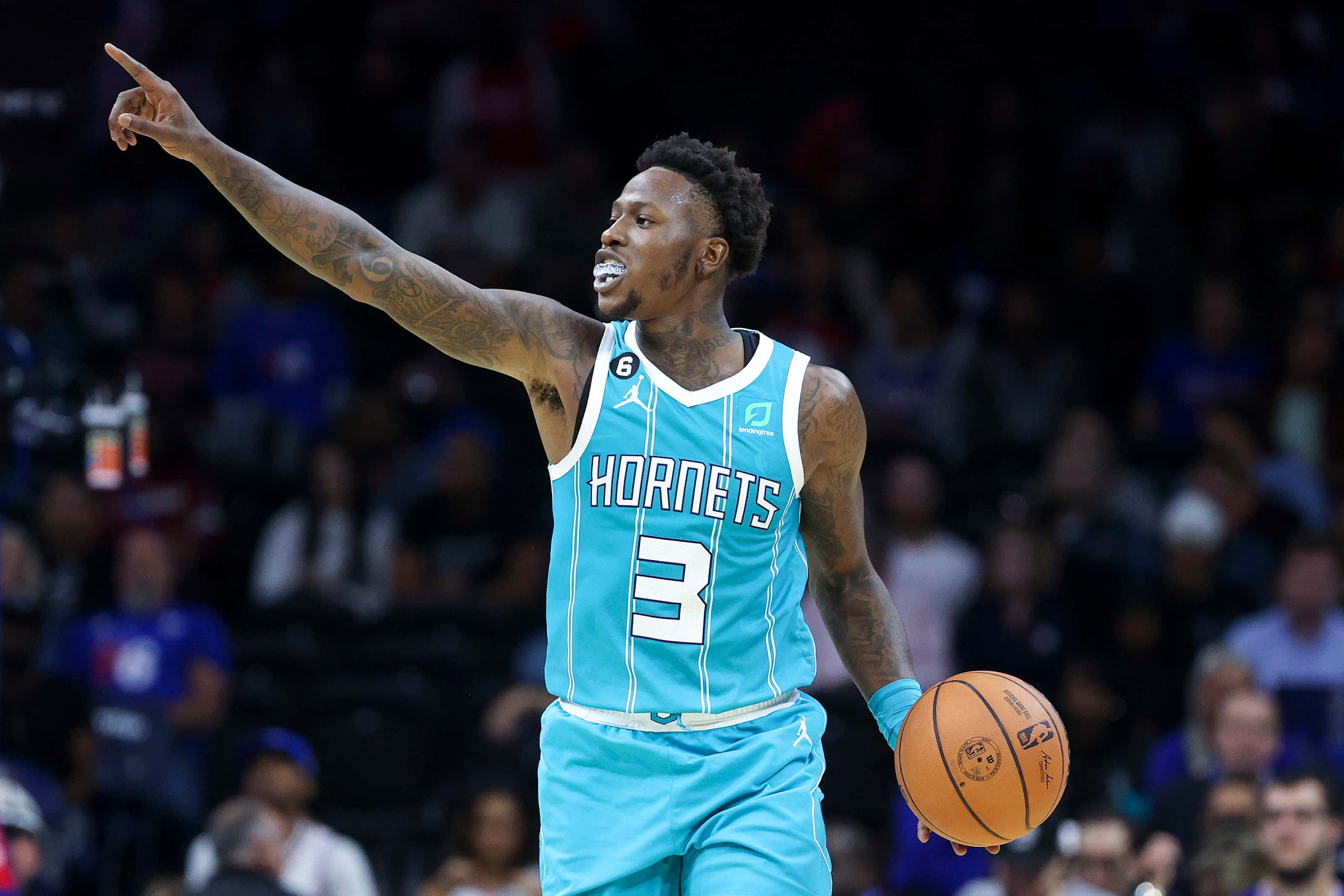NBA 桌布 壁紙 — 一位身穿青綠色球衣的夏洛特黃蜂隊籃球運動員在場館燈光下比賽時，手持籃球向上指。