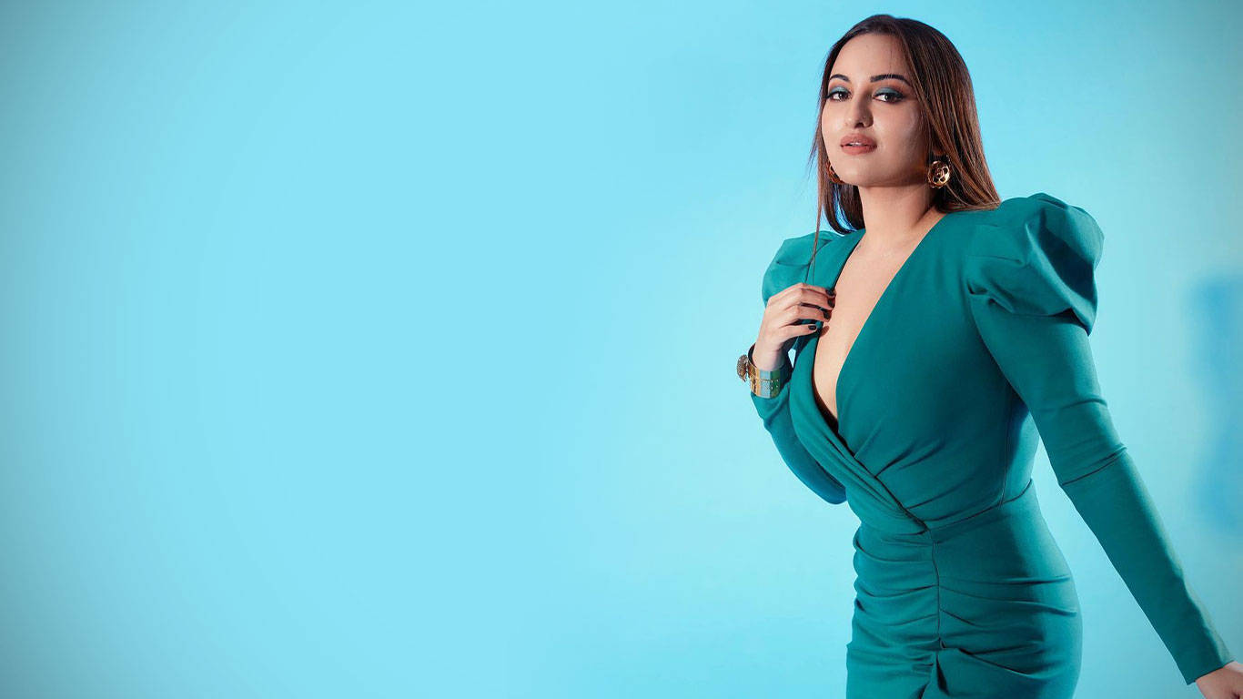 Sonakshi Sinha 桌布 壁紙 — 一位身穿青綠色連衣裙的女性在純色淺藍色攝影棚背景前自信地擺姿勢。