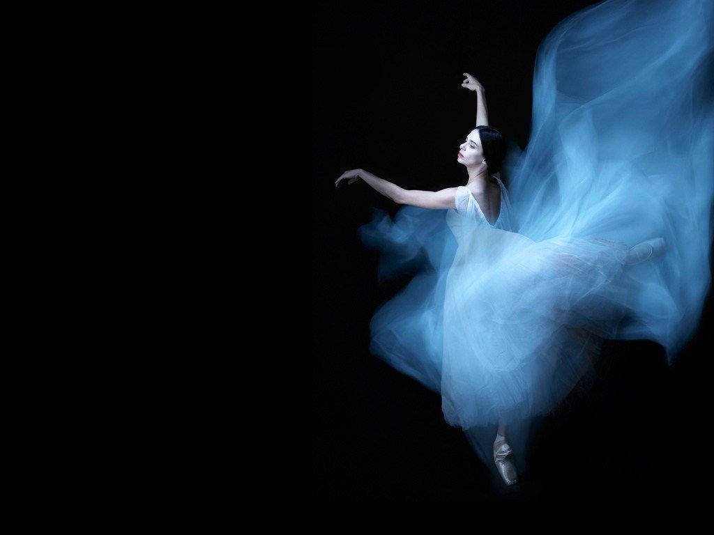 Ballet 桌布 壁紙 — 一位身穿飄逸白色芭蕾舞裙的芭蕾舞者，在漆黑的背景與空靈的藍色燈光下優雅起舞。