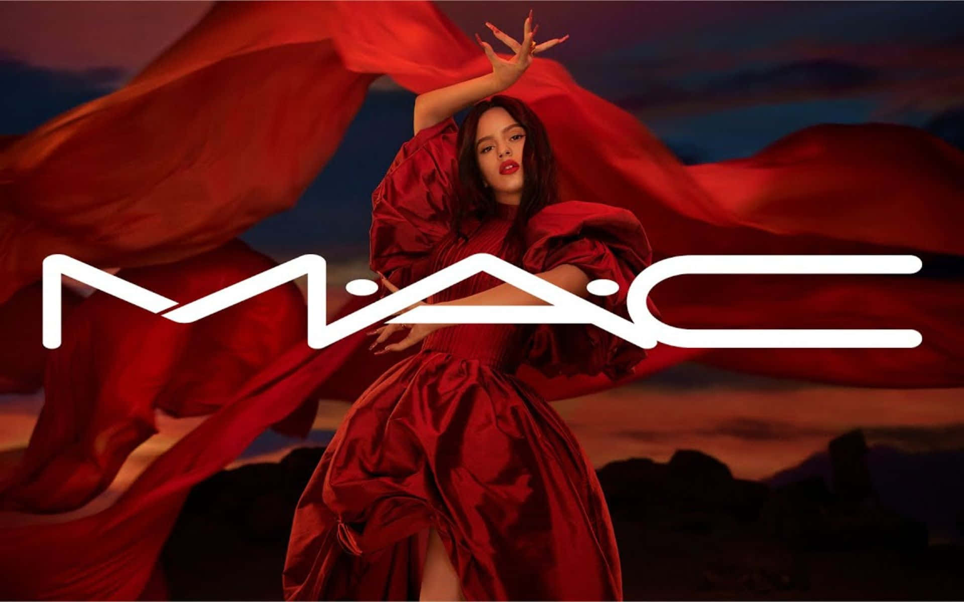 Mac Cosmetics 桌布 壁紙 — 一位身穿飄逸紅裙的女性在暮色天空下戲劇性地擺姿勢，並疊加了MAC標誌。