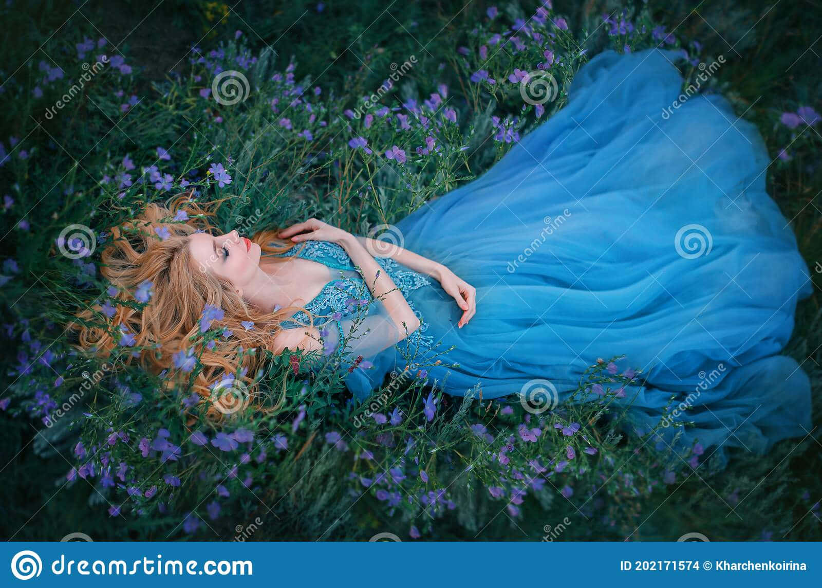 sleeping beauty 桌布 壁紙 — 一位身穿飄逸藍色長裙的女性，在翠綠的草地上，安詳地躺在紫色野花叢中。