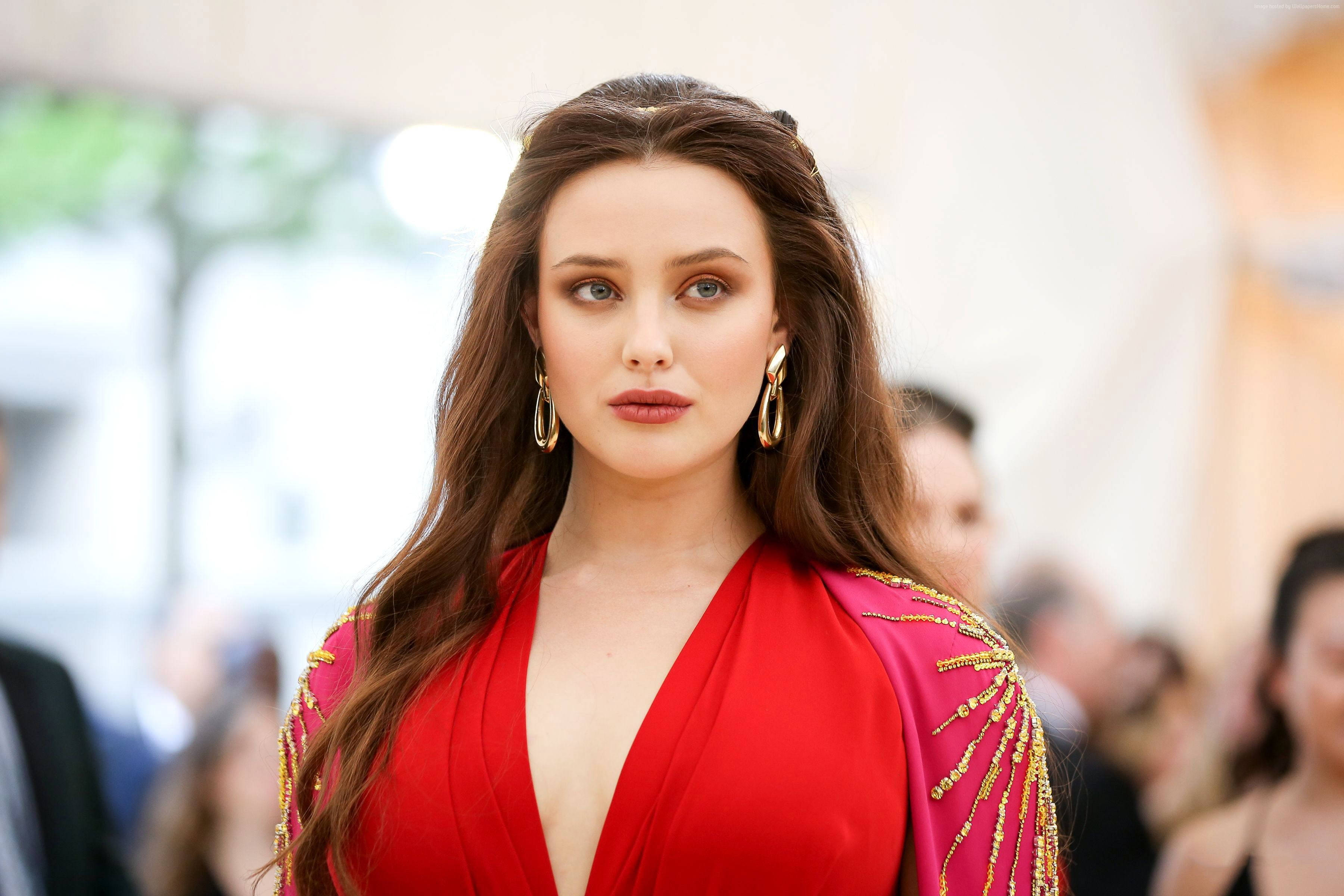 Katherine Langford 桌布 壁紙 — 一位身穿鮮紅色禮服、肩部飾有金色珠飾的女性，以沉穩的表情直視鏡頭。