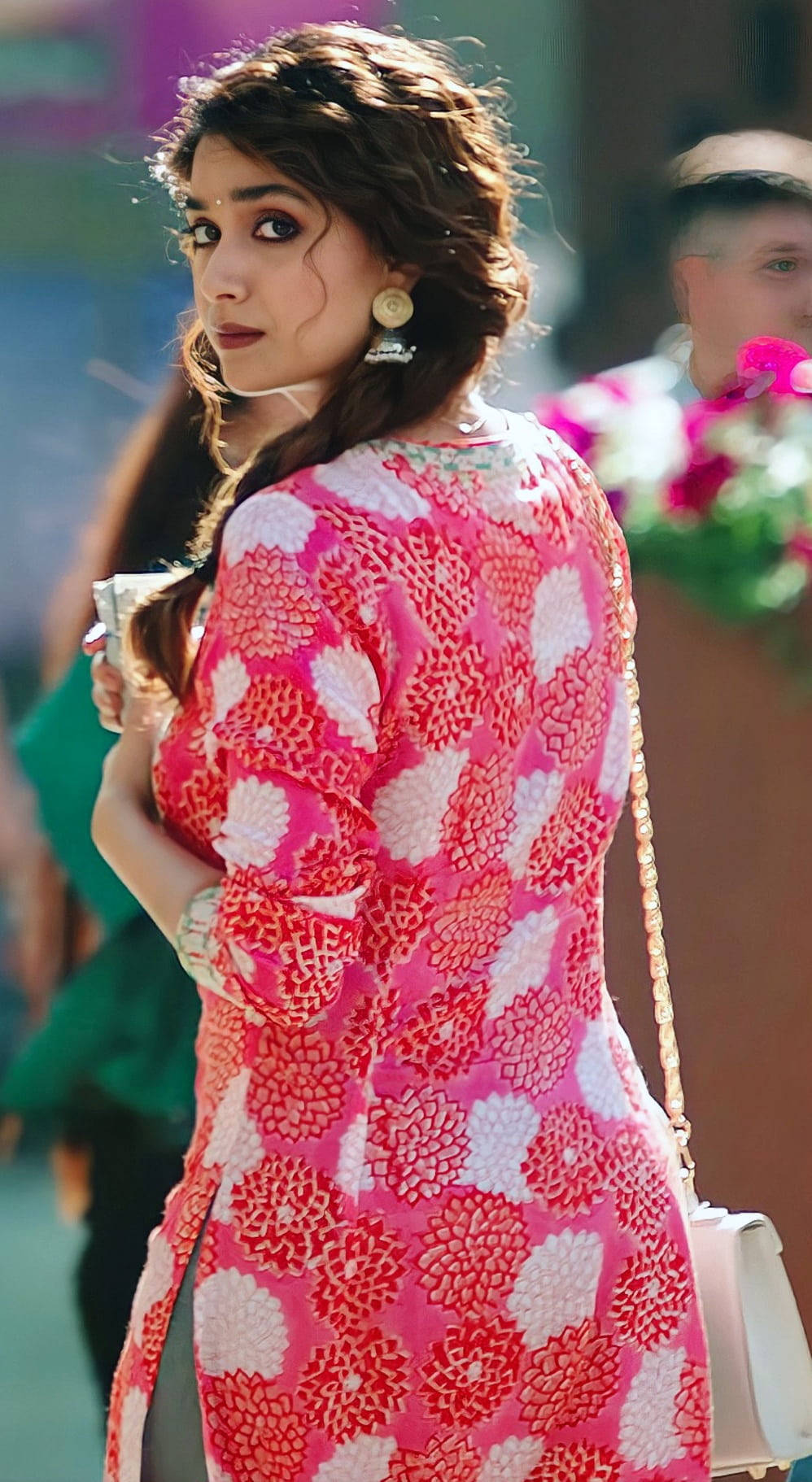telugu 桌布 壁紙 — 一位身穿鮮豔粉紅色花卉連衣裙的女性轉頭越過肩膀回望，表情若有所思。
