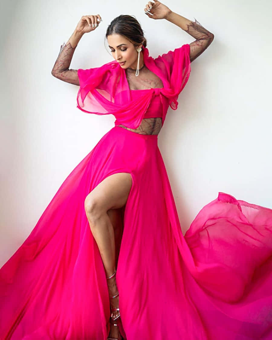 Pink Fashion 桌布 壁紙 — 一位身穿鮮豔紫紅色兩件式長袍、搭配透視袖和高開衩的女性，自信地在純白牆壁前擺姿勢。