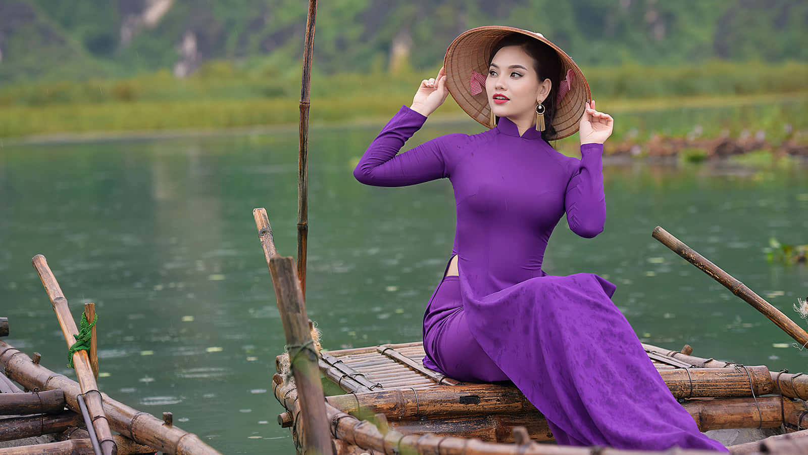 Vietnam 桌布 壁紙 — 一位身穿鮮豔紫色奧黛和錐形帽的女子優雅地坐在漂浮在寧靜綠色湖面上的竹筏上。