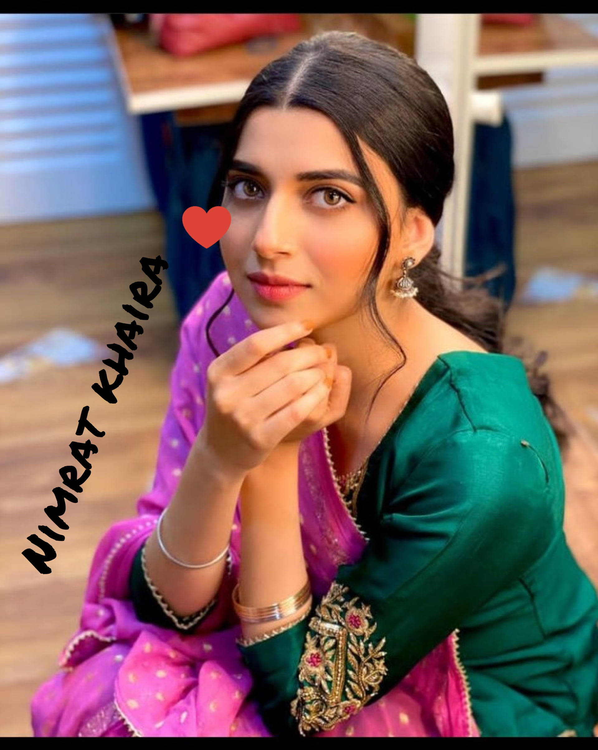 Indian 桌布 壁紙 — 一位身穿鮮豔綠色和粉紅色傳統服飾的女性，帶著溫柔的微笑，手靠近下巴擺姿勢。