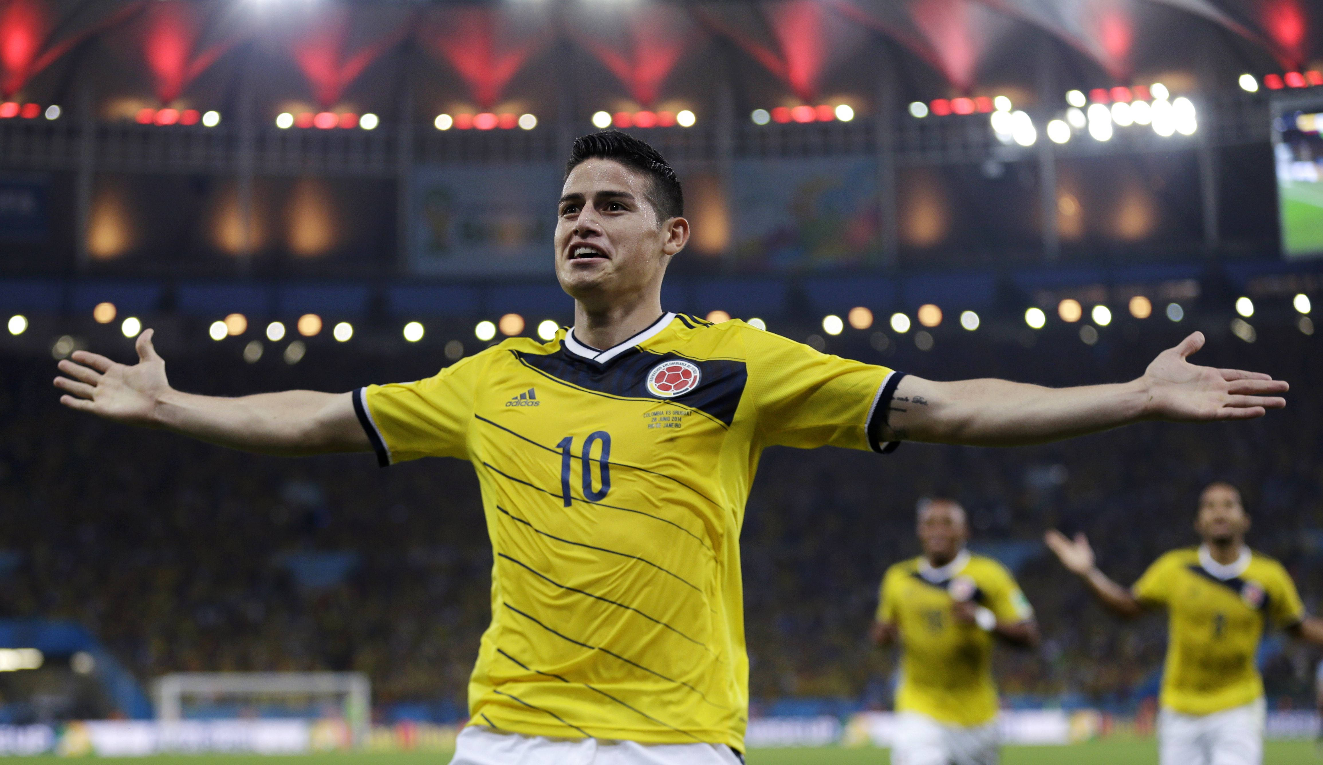 James Rodriguez 桌布 壁紙 — 一位身穿黃色10號球衣的哥倫比亞足球員在球場燈光下張開雙臂慶祝。