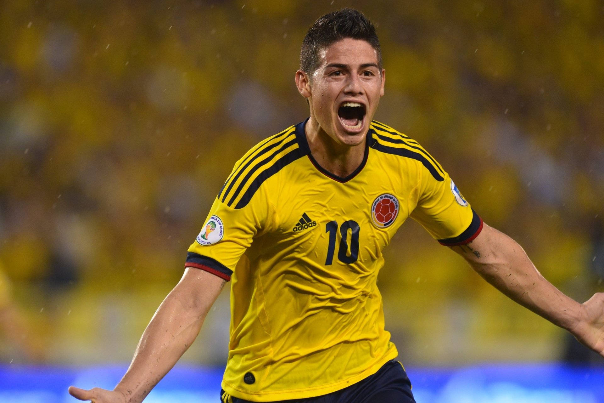 James Rodriguez 桌布 壁紙 — 一位身穿黃色10號球衣的哥倫比亞足球員在球場燈光下張開雙臂熱情慶祝。