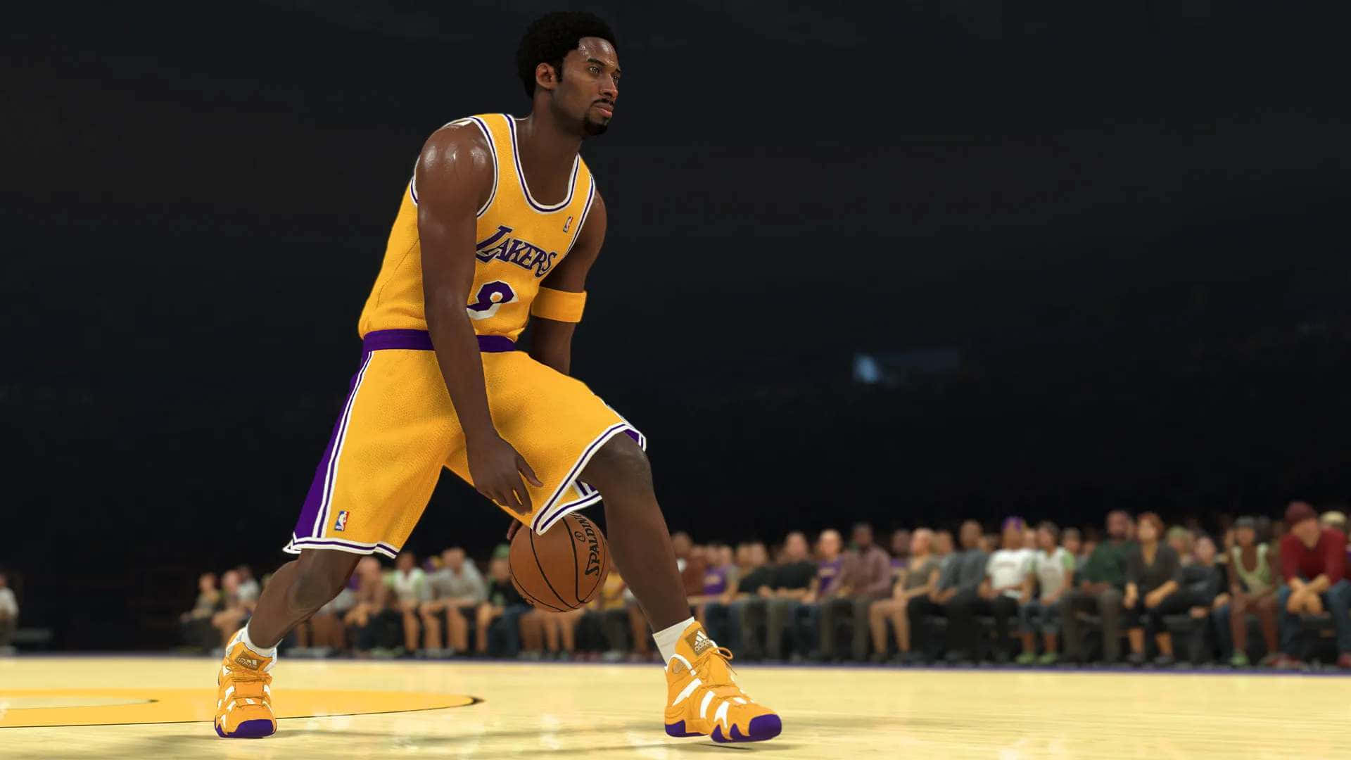 NBA 2k21 桌布 壁紙 — 一位身穿黃色湖人隊球衣的籃球運動員在燈光明亮的球場上運球，背景是模糊的人群。