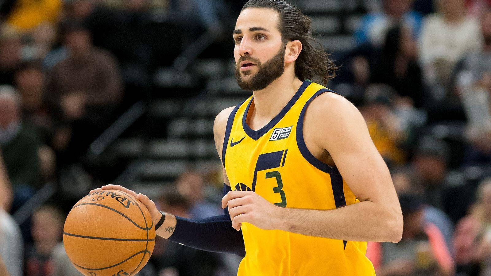 Ricky Rubio 桌布 壁紙 — 一位身穿黃色球衣、專注的籃球運動員在明亮的場館燈光下，於激烈的比賽中運球。