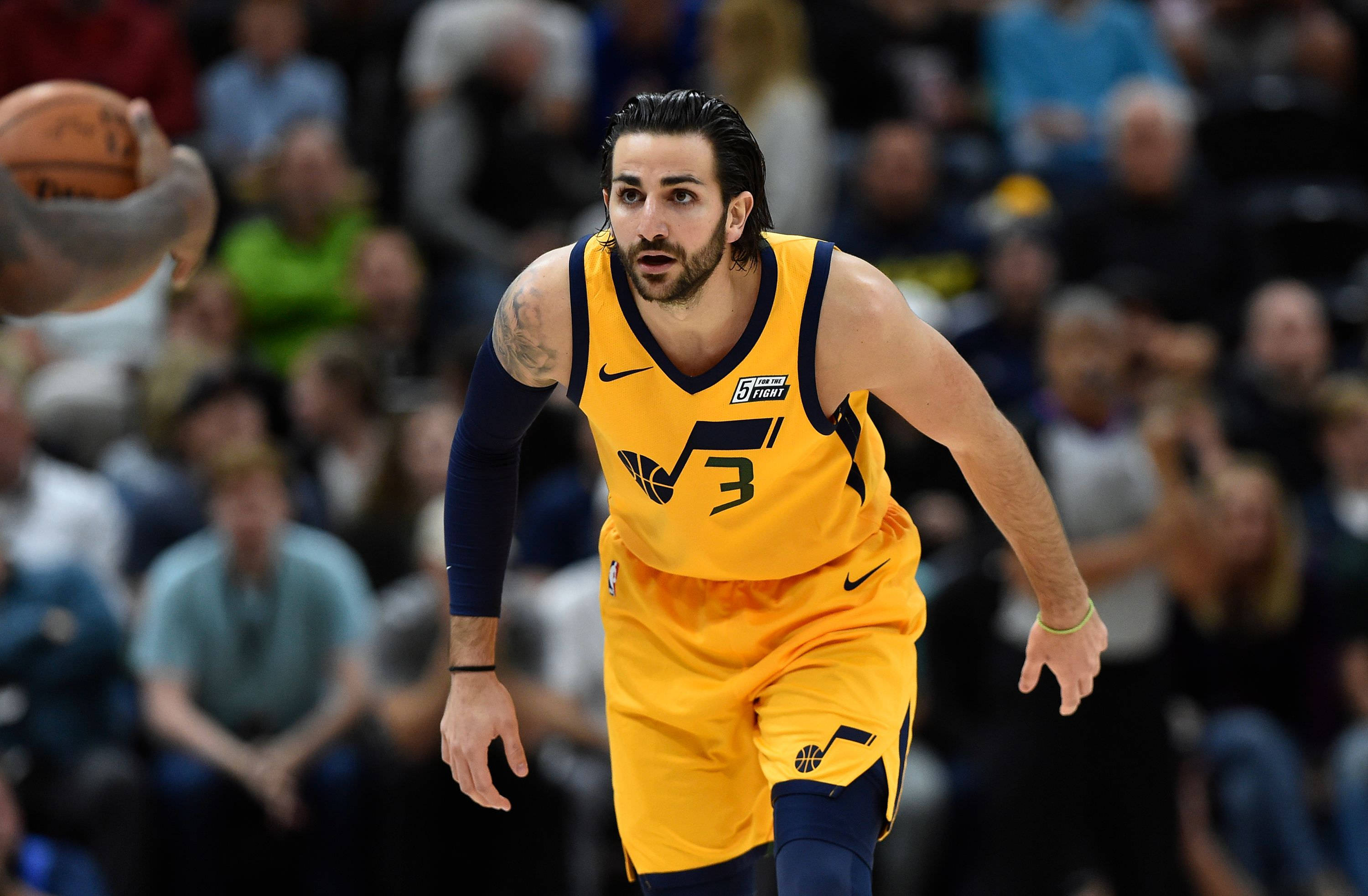 Ricky Rubio 桌布 壁紙 — 一位身穿黃色球衣的專注籃球運動員在比賽中激烈運球，背景是模糊的人群。