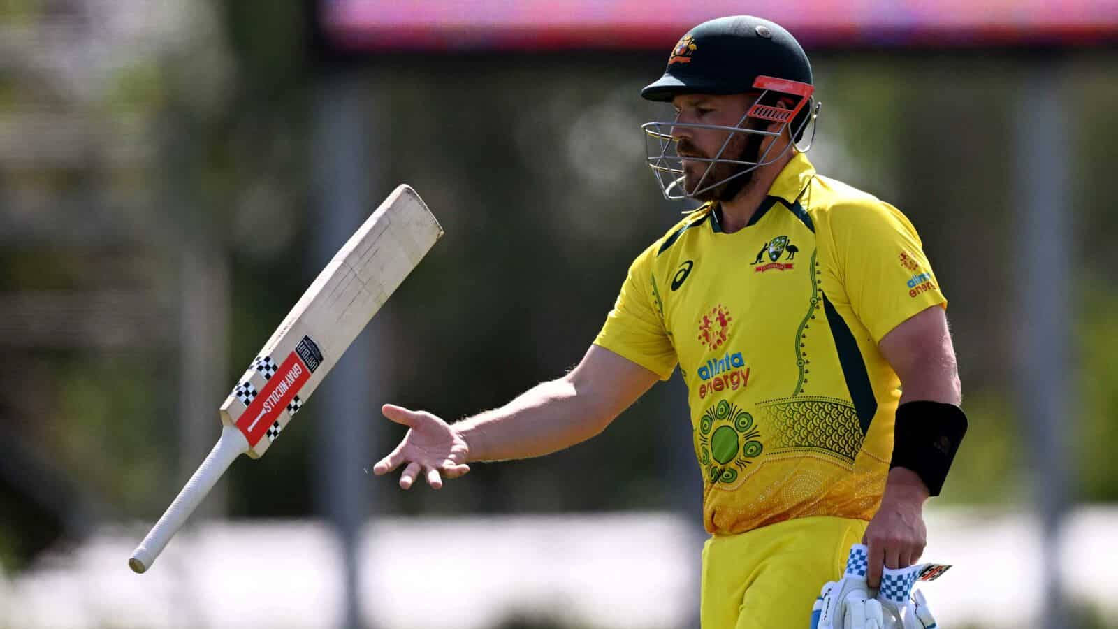 Aaron Finch 桌布 壁紙 — 一位身穿黃色球衣的澳洲板球運動員在陽光明媚的比賽中，專注地將球棒拋向空中。