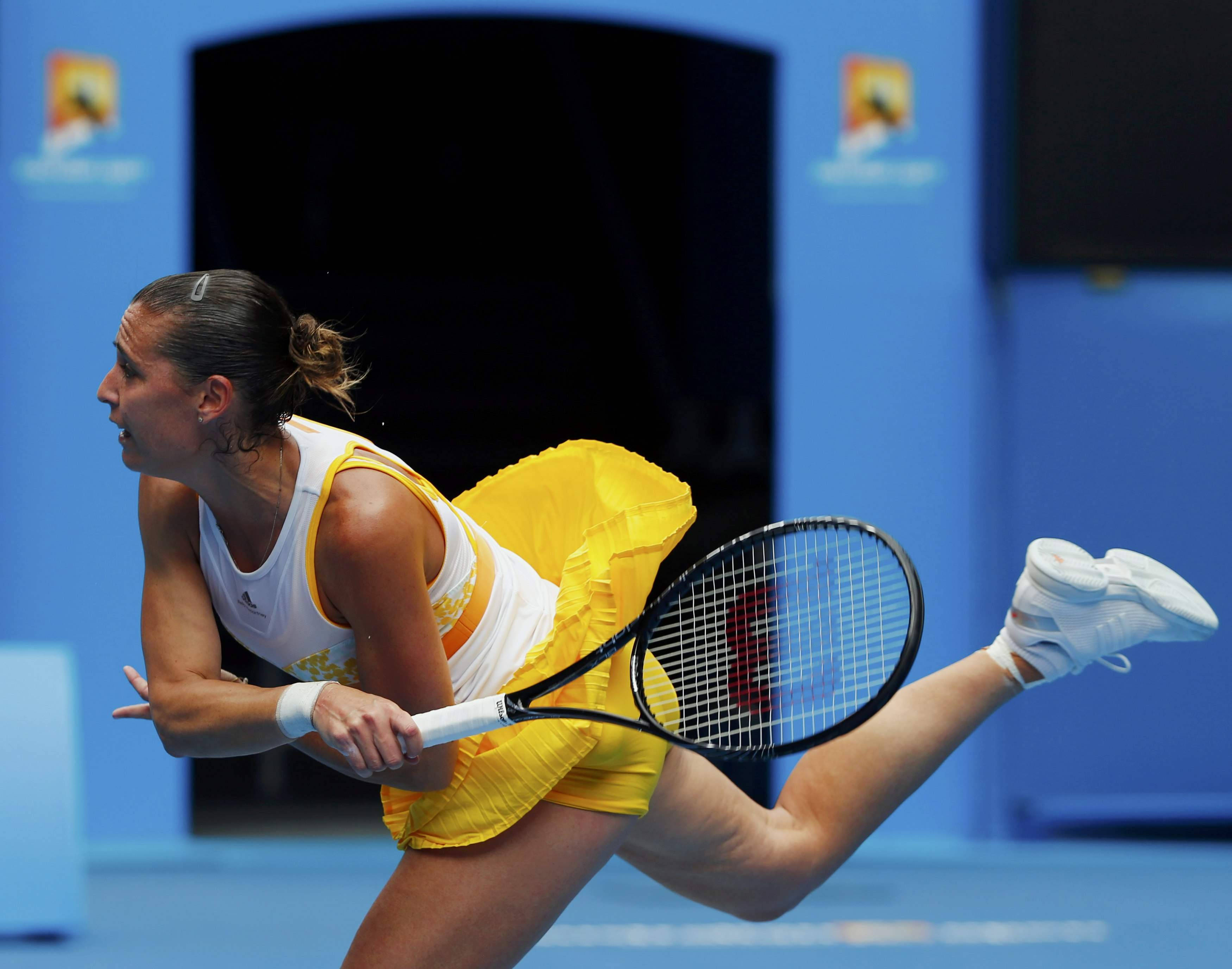 Athletic 桌布 壁紙 — 一位身穿黃色裙的女網球選手在藍色球場上進行激烈比賽時，用球拍做出動態的弓箭步動作。