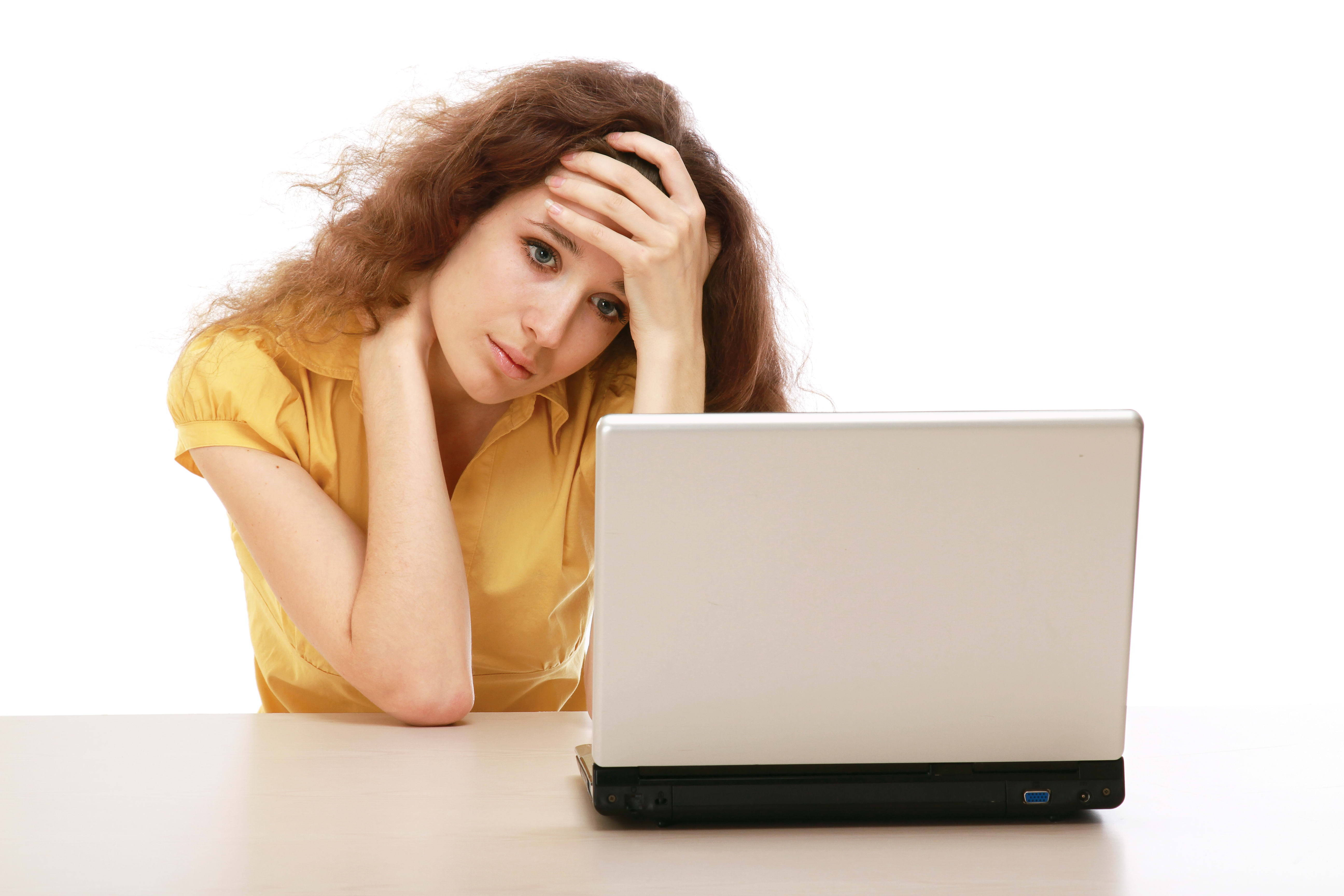 tired 桌布 壁紙 — 一位身穿黃色襯衫的女士，在白色桌上的筆記型電腦前用手托著頭，看起來壓力很大。