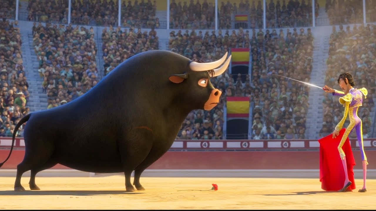 Animated 桌布 壁紙 — 一位身穿黃色西裝的卡通鬥牛士在陽光明媚的鬥牛場上，面對一頭巨大的黑牛，觀眾歡呼雀躍。