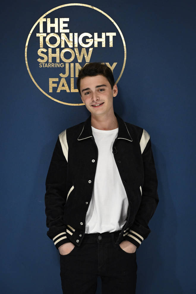 Celebrity 桌布 壁紙 — 一位身穿黑白棒球外套的年輕男子在帶有The Tonight Show標誌的藍色背景前自信微笑。